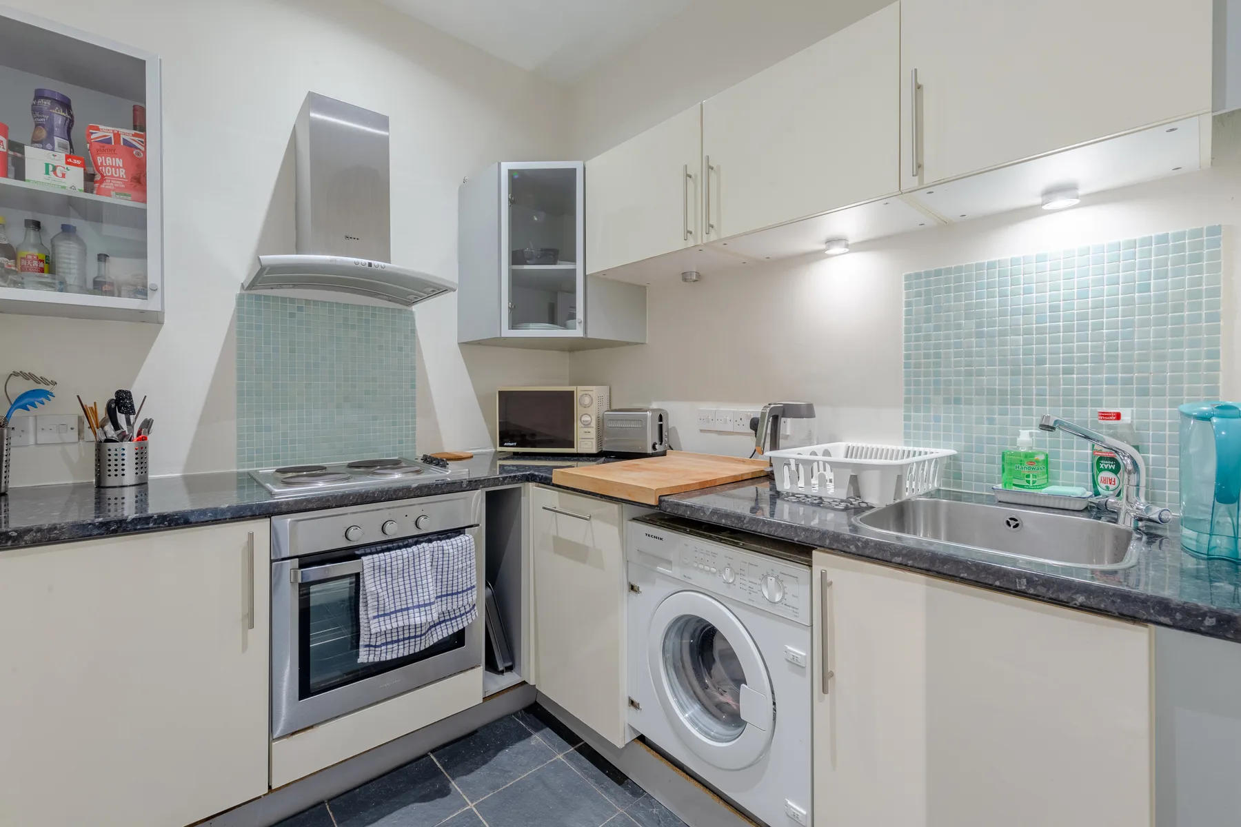 A bright kitchen with counters, a sink, and built-in appliances.