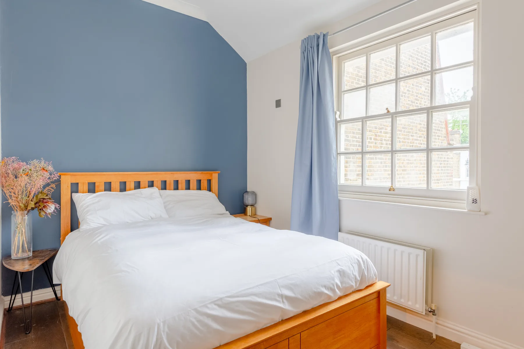 Un dormitorio con una cama de madera bajo una ventana grande.