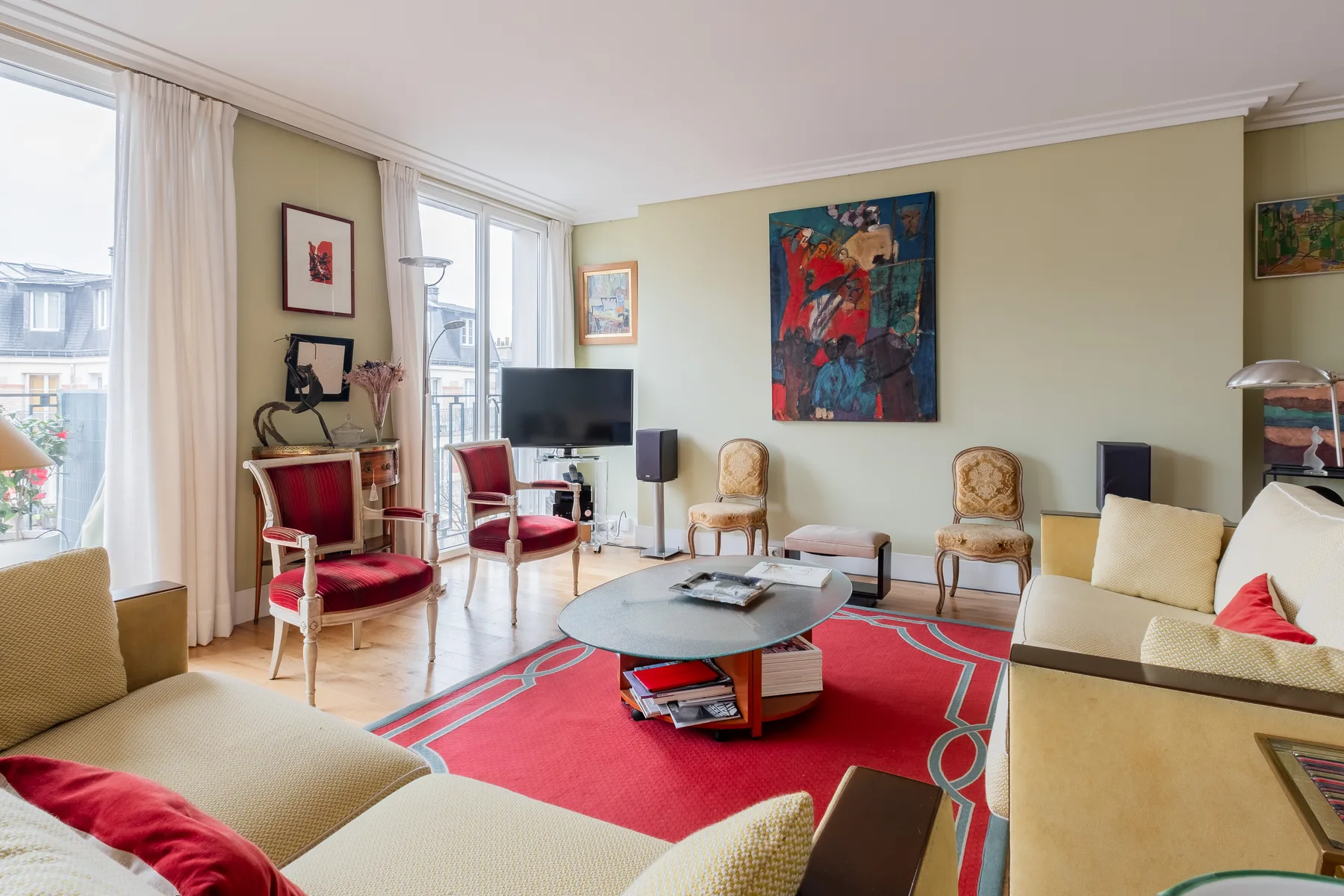 Sala de estar con asientos alrededor de una mesa de centro sobre una alfombra roja.