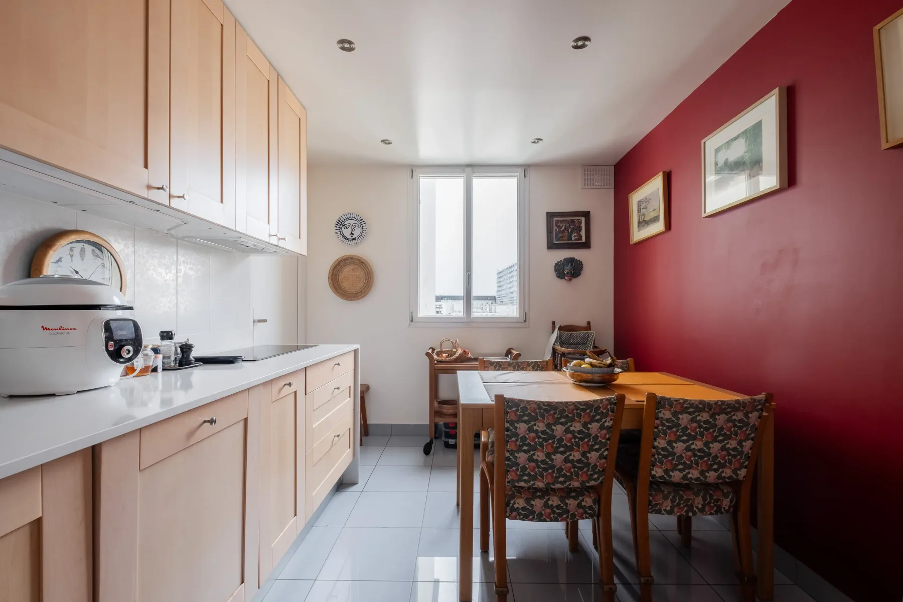 A kitchen and dining area with pale cabinets, a table, and patterned seating.