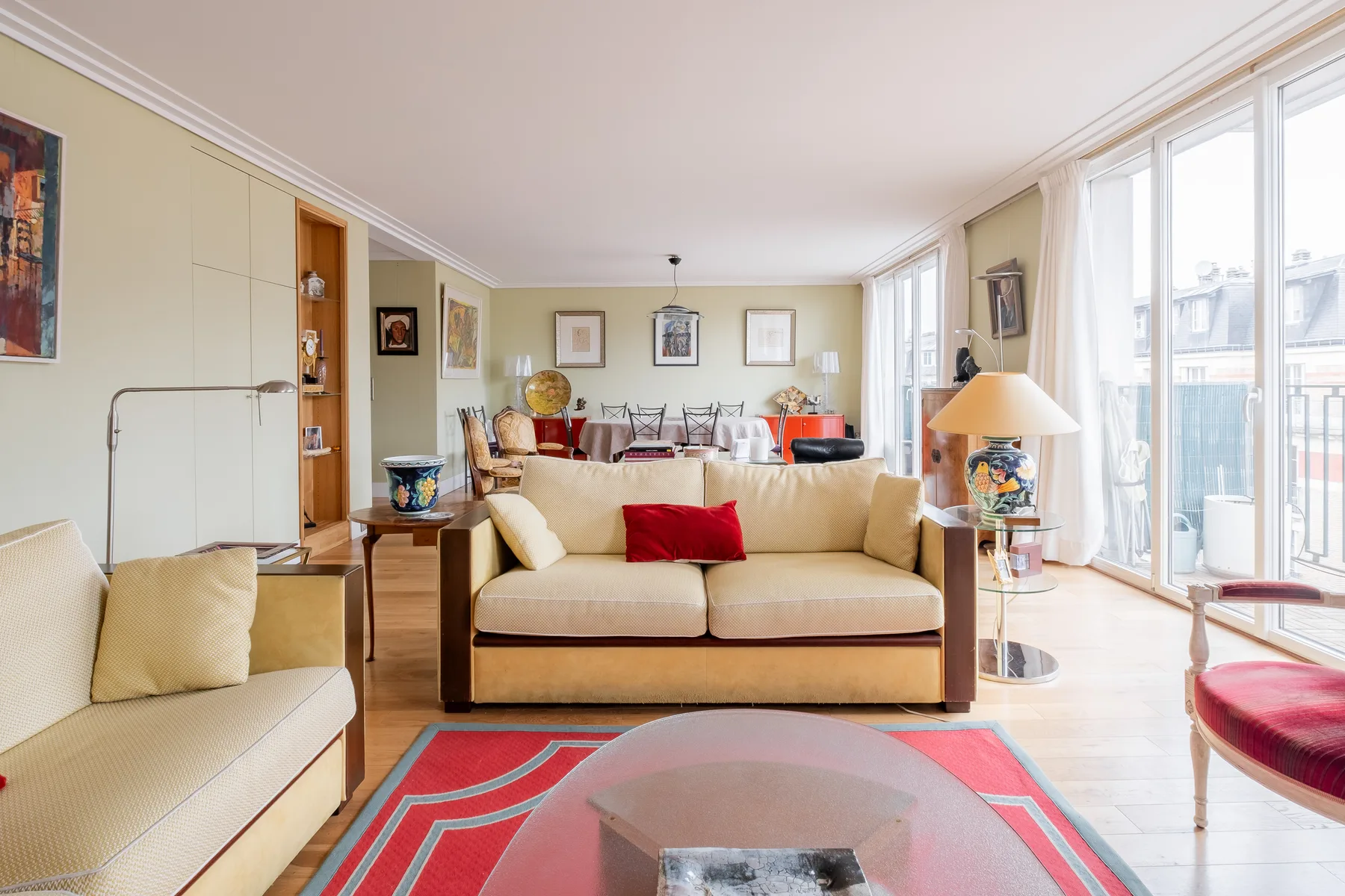 Una luminosa sala de estar con sofá, grandes ventanas y una alfombra colorida.