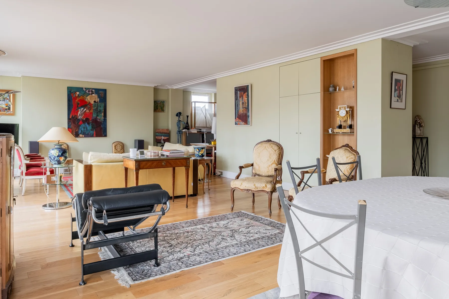 A bright living and dining area with seating, a table, and built-in cabinets.