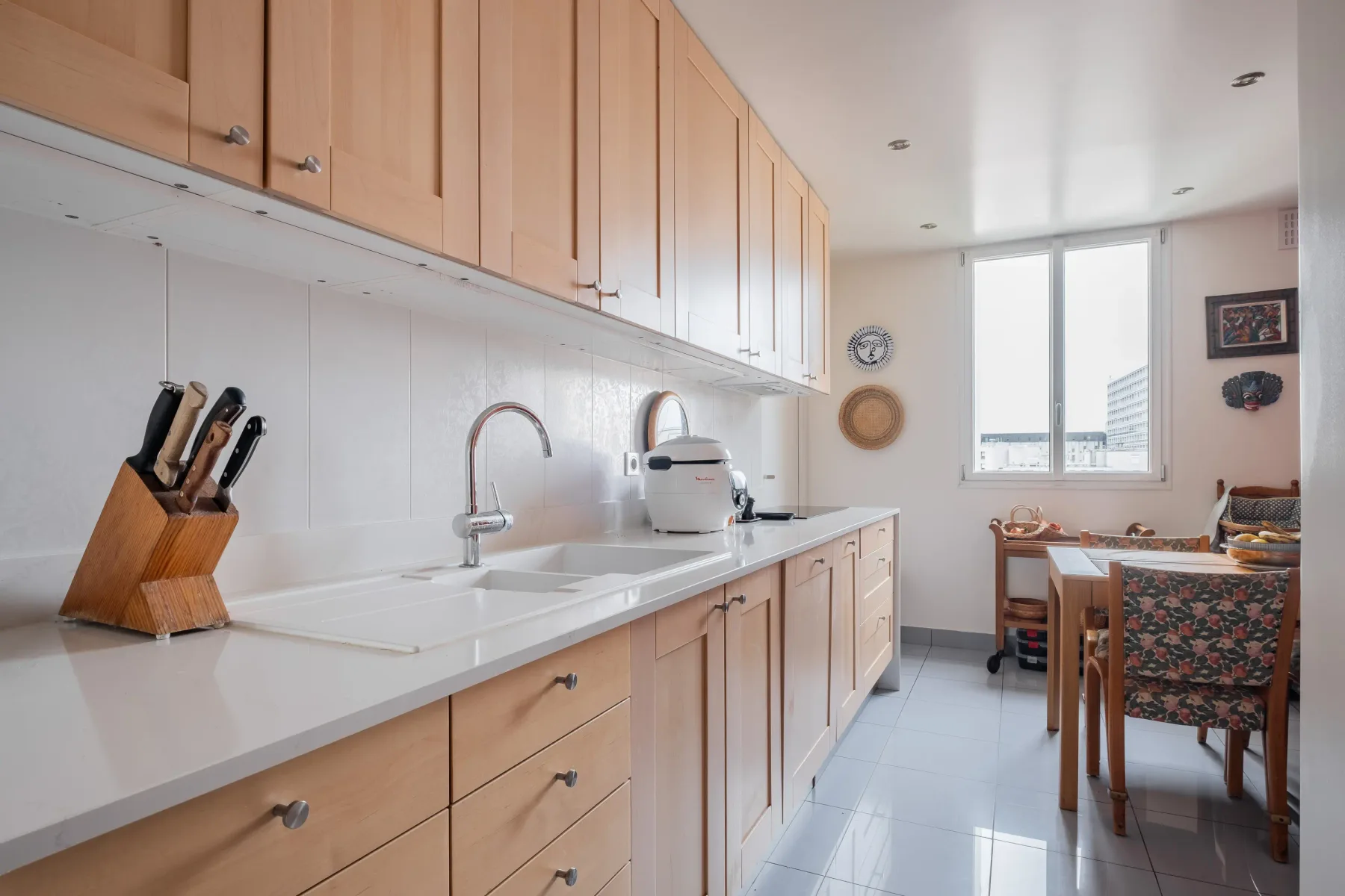 A bright kitchen with wooden cabinets and a long countertop.