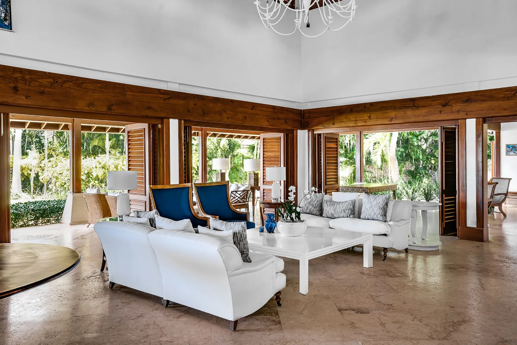 A bright living room with seating arranged around a white coffee table and large windows.