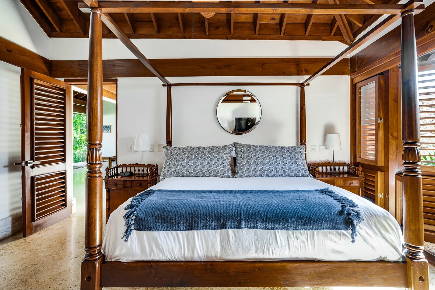 Un dormitorio con una cama grande bajo un dosel de madera oscura.