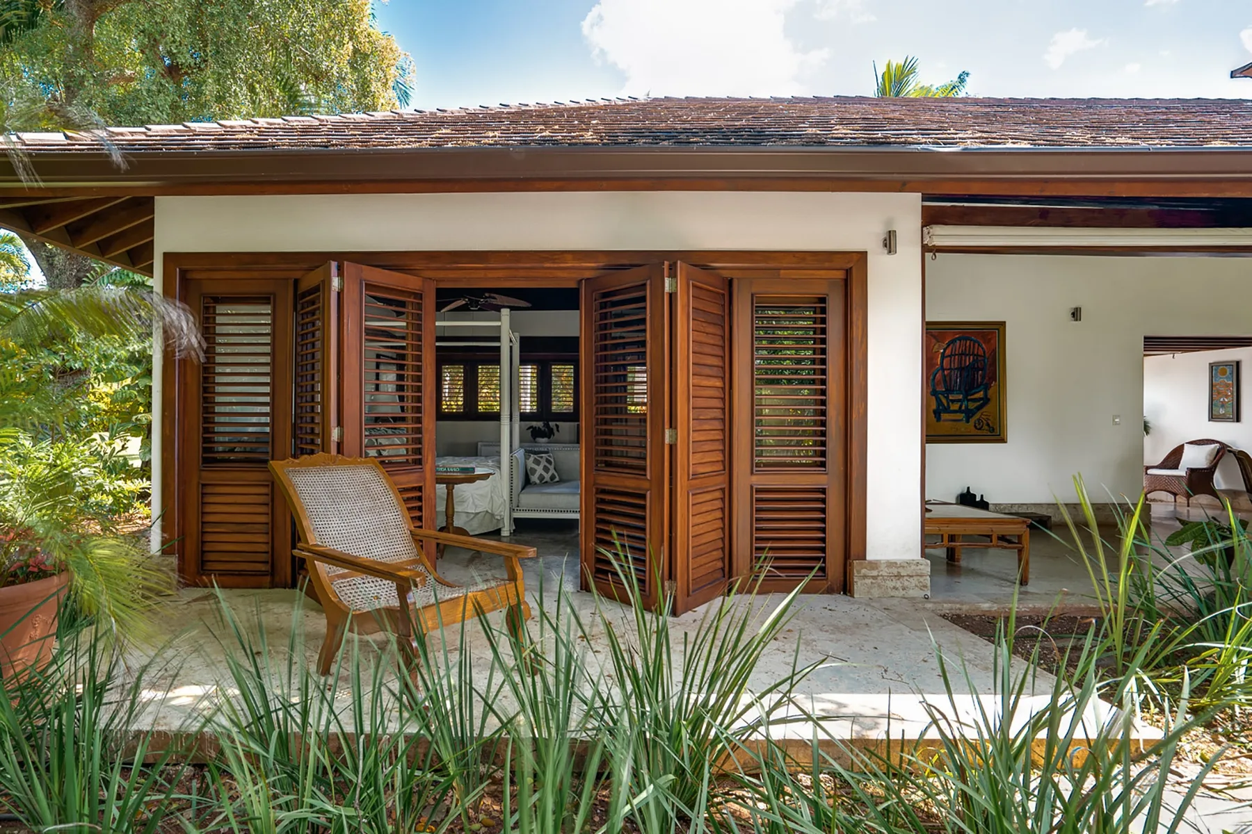 Exterior de una casa con contraventanas de madera abiertas y un pequeño patio.