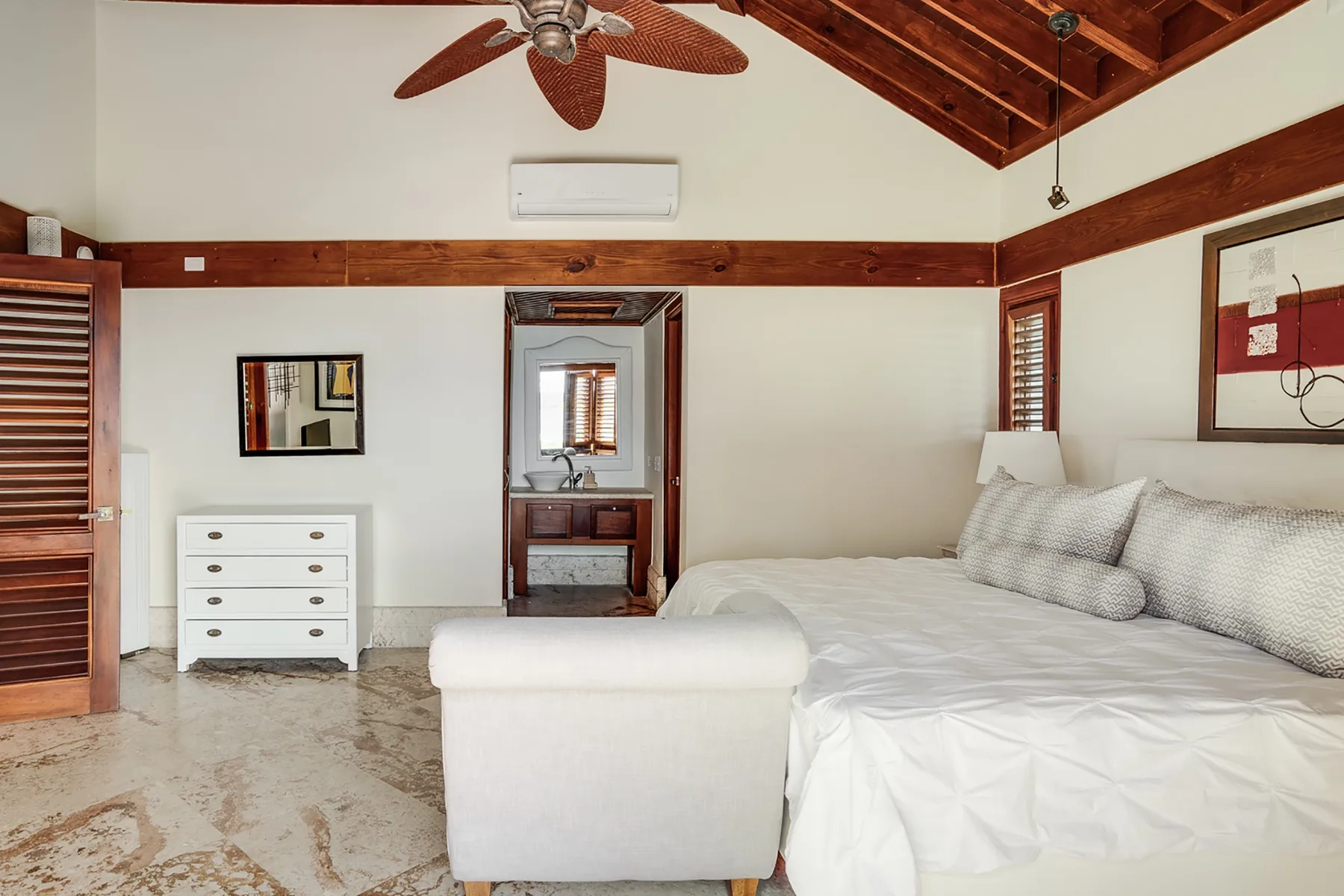Un dormitorio con una cama grande y una cómoda blanca.