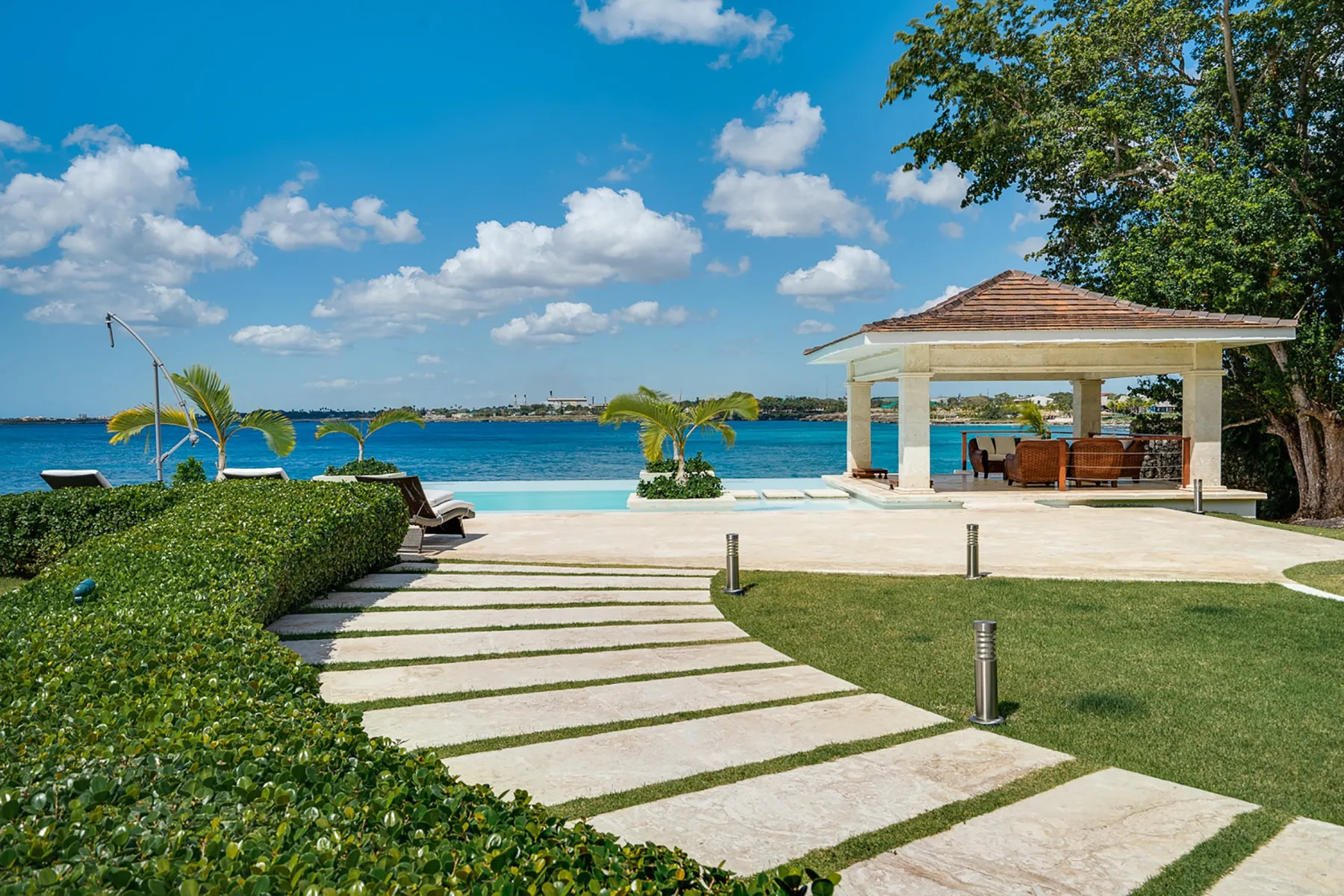 Un patio ajardinado junto al mar, con una zona de estar cubierta.
