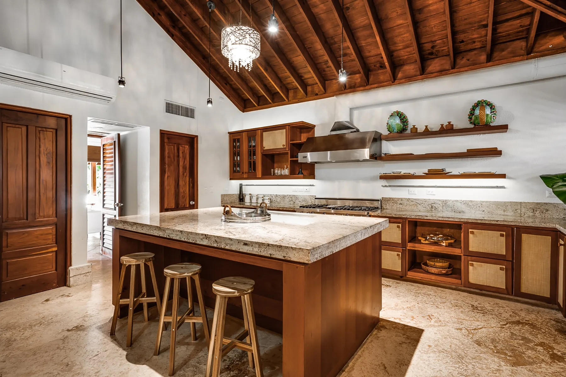 A spacious kitchen with a large central island beneath a wooden ceiling.