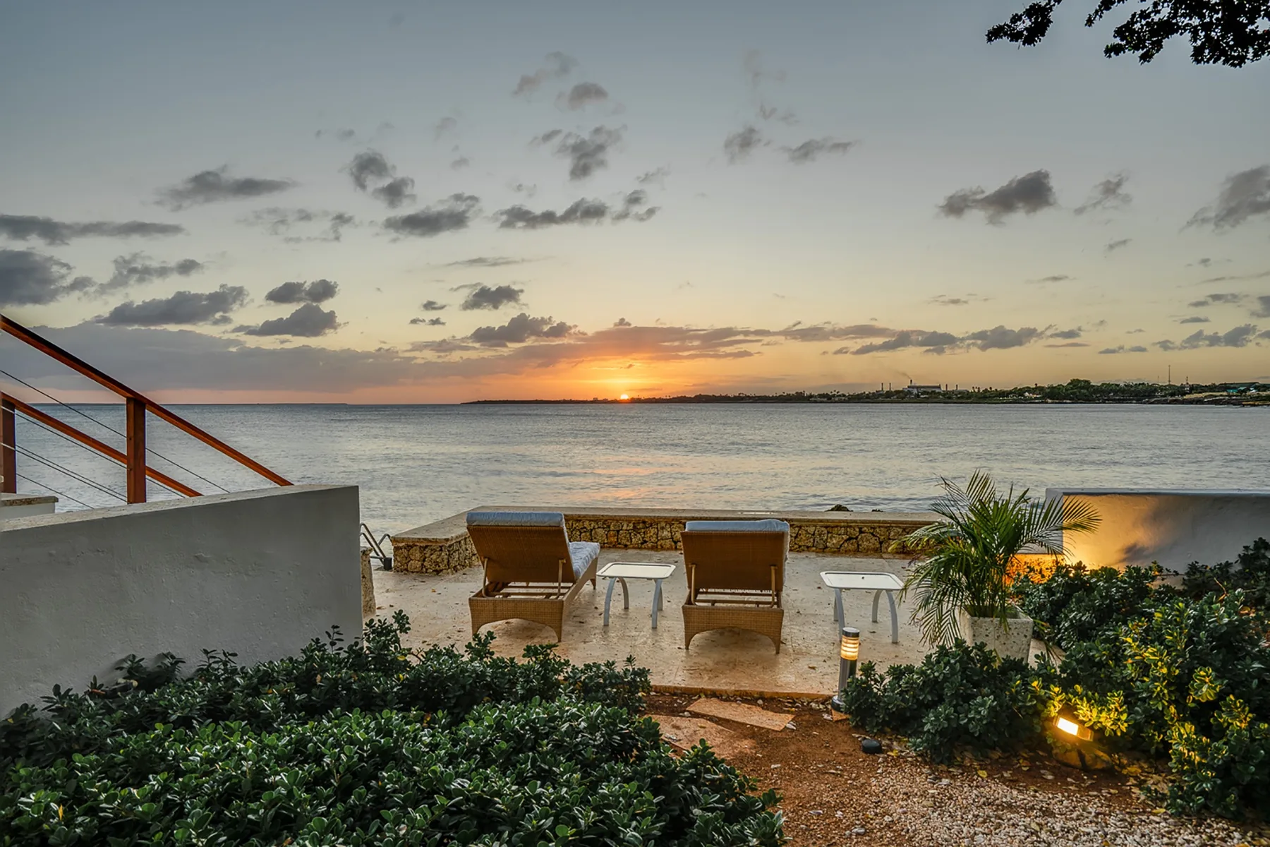 Waterfront patio with seating overlooks the water at sunset.