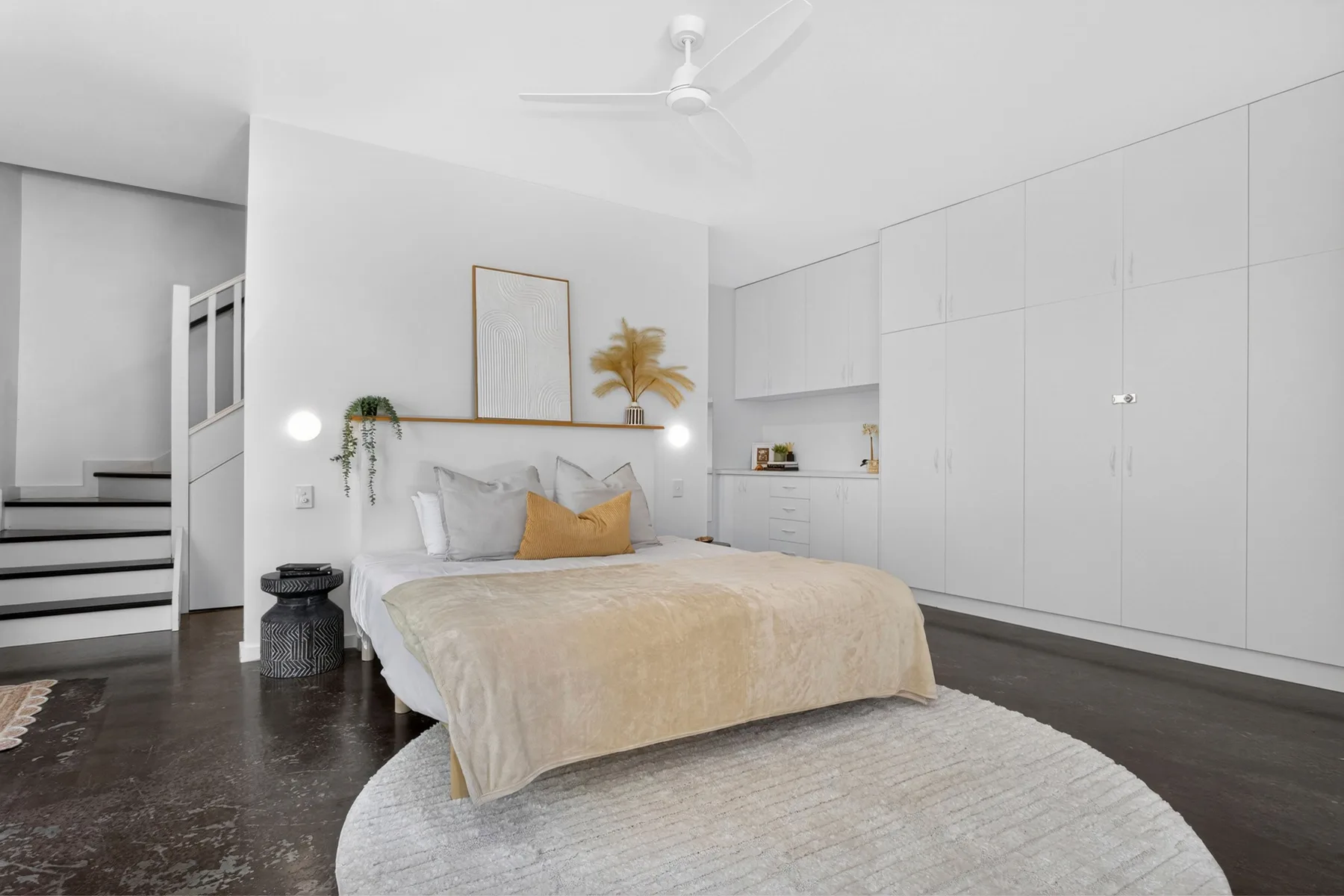 Un dormitorio luminoso con cama, iluminación junto a la cama y almacenamiento empotrado.