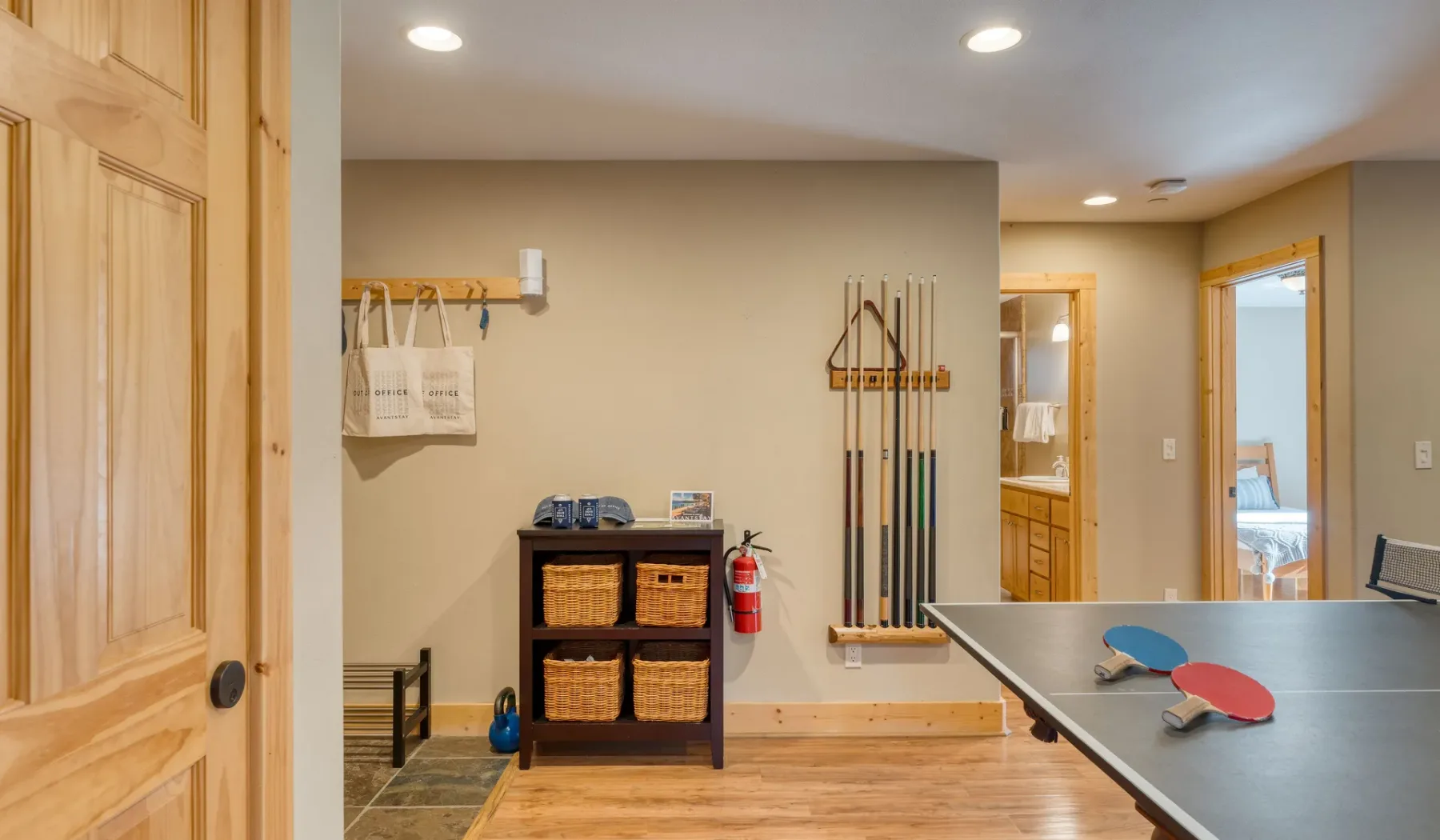 A recreation room with a pool table, cue rack, and storage baskets.