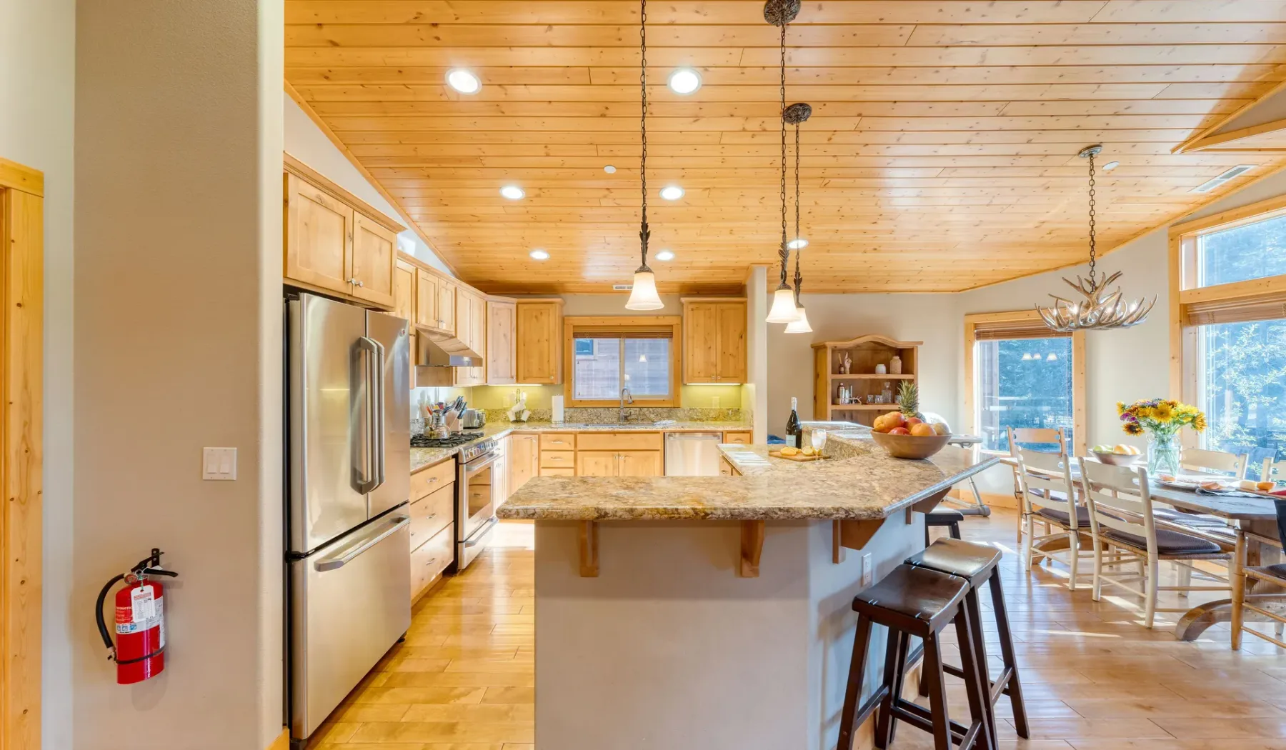 An open kitchen and dining area with a large island and wooden ceiling.