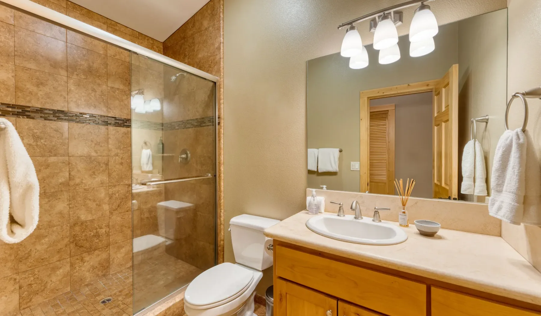 A bathroom with a glass shower, toilet, and vanity with a sink.