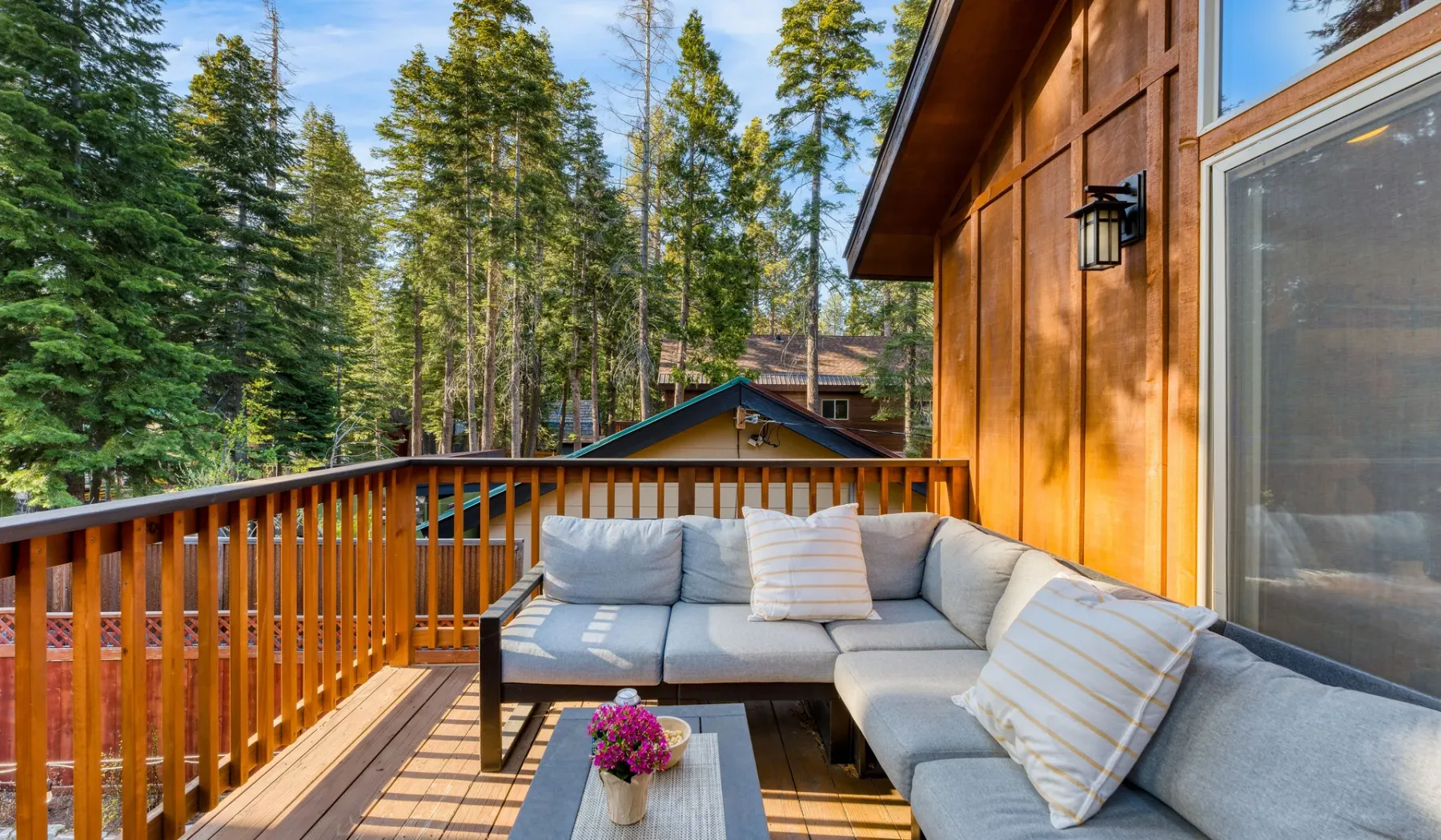 A wooden deck with outdoor seating and trees surrounding the cabin.