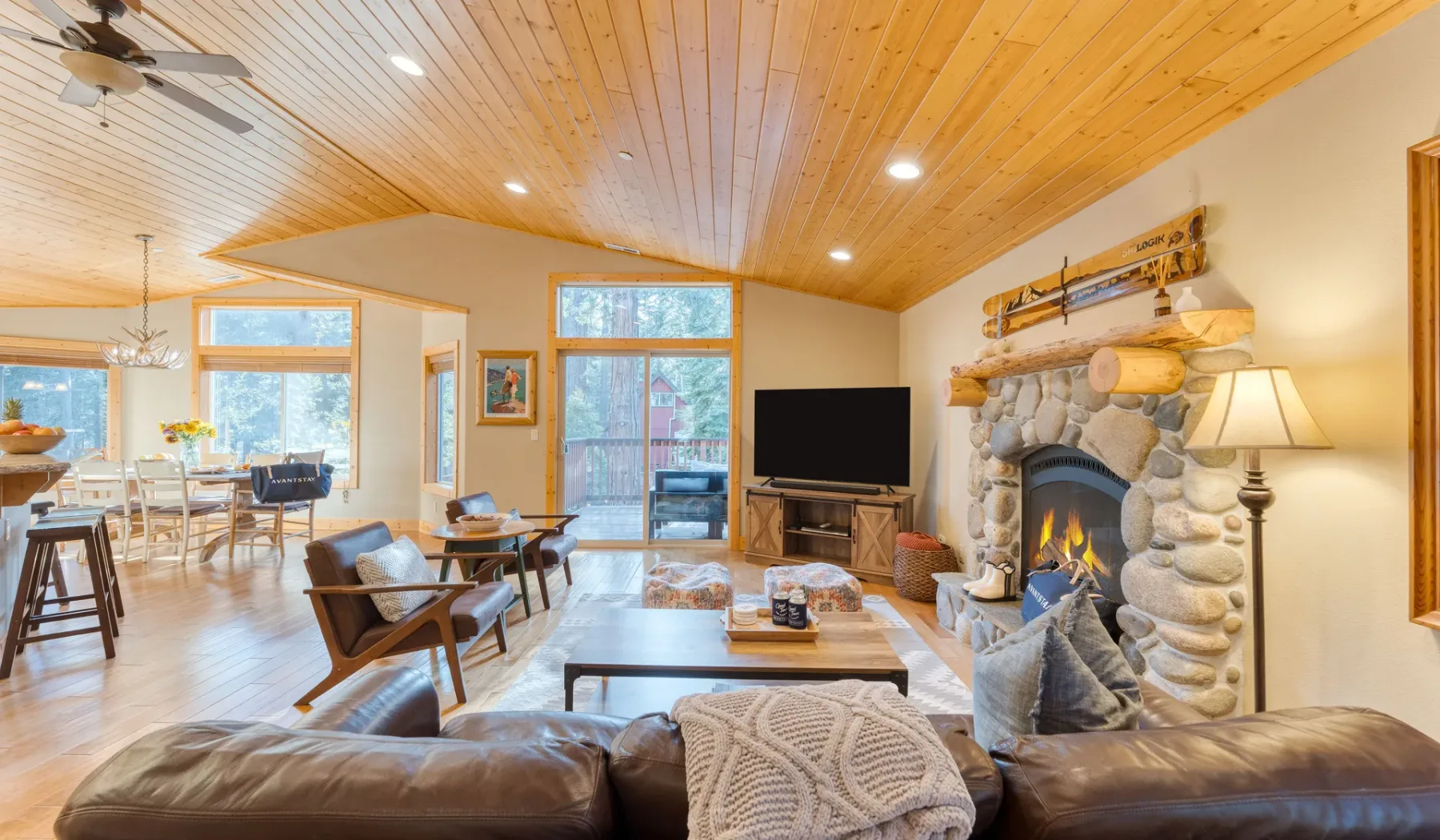 A living room with a stone fireplace, seating, and an open dining area.