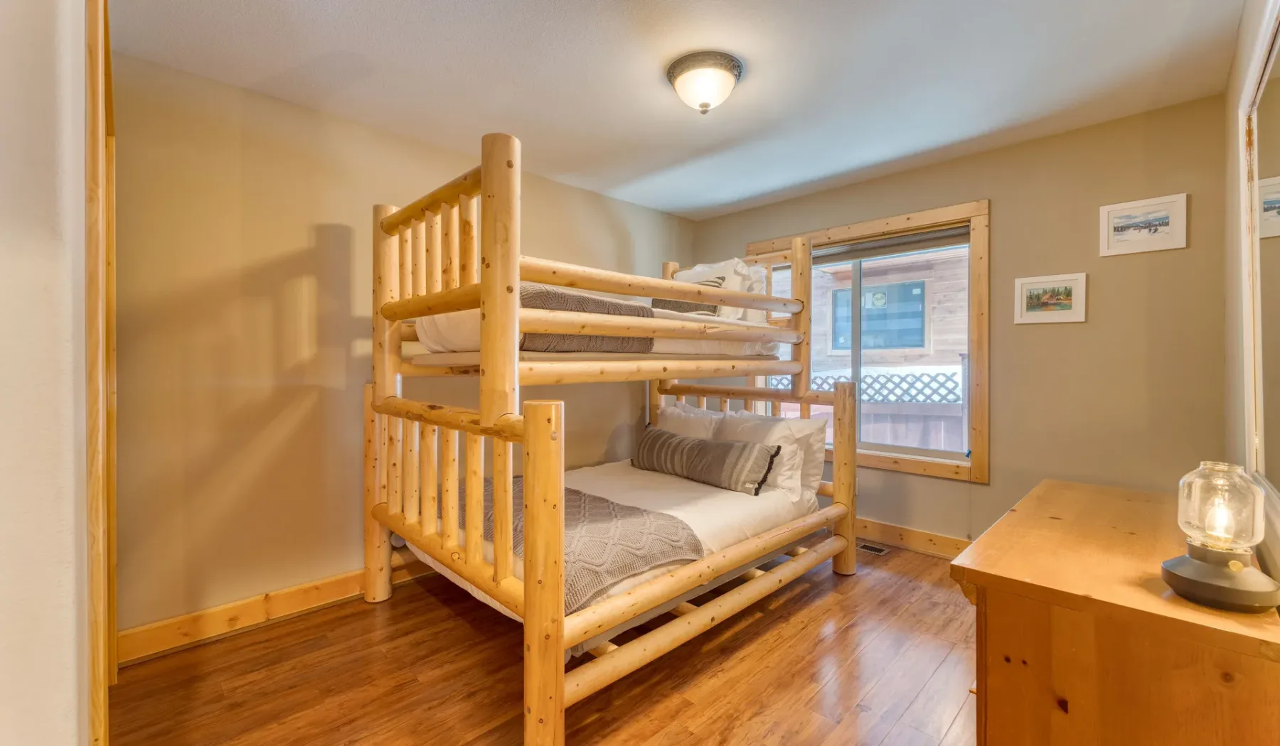 A bedroom with a wooden bunk bed beside a window.