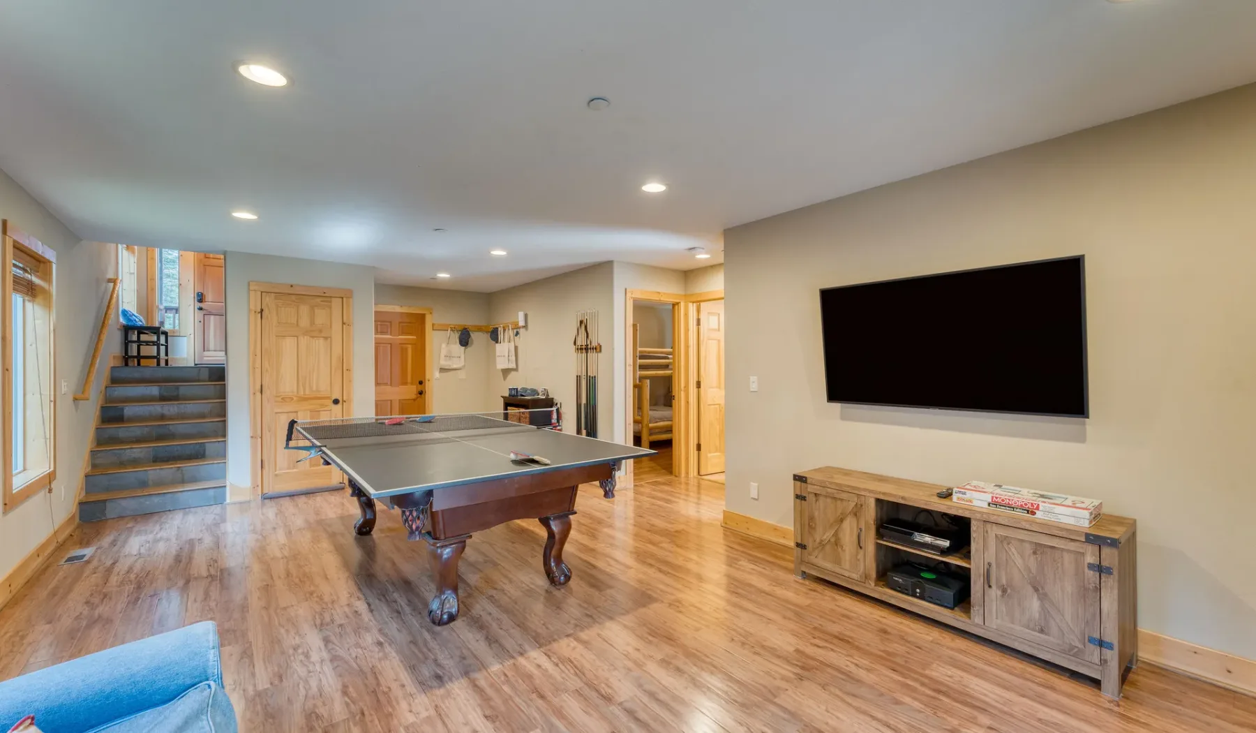 A recreation room with a ping-pong table and a wall-mounted television.