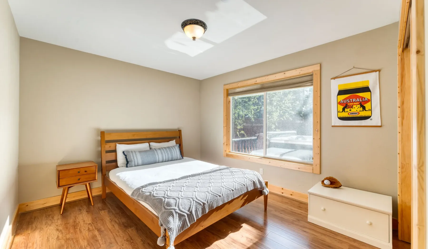 A bedroom with a wooden bed, patterned bedding, and a large window.