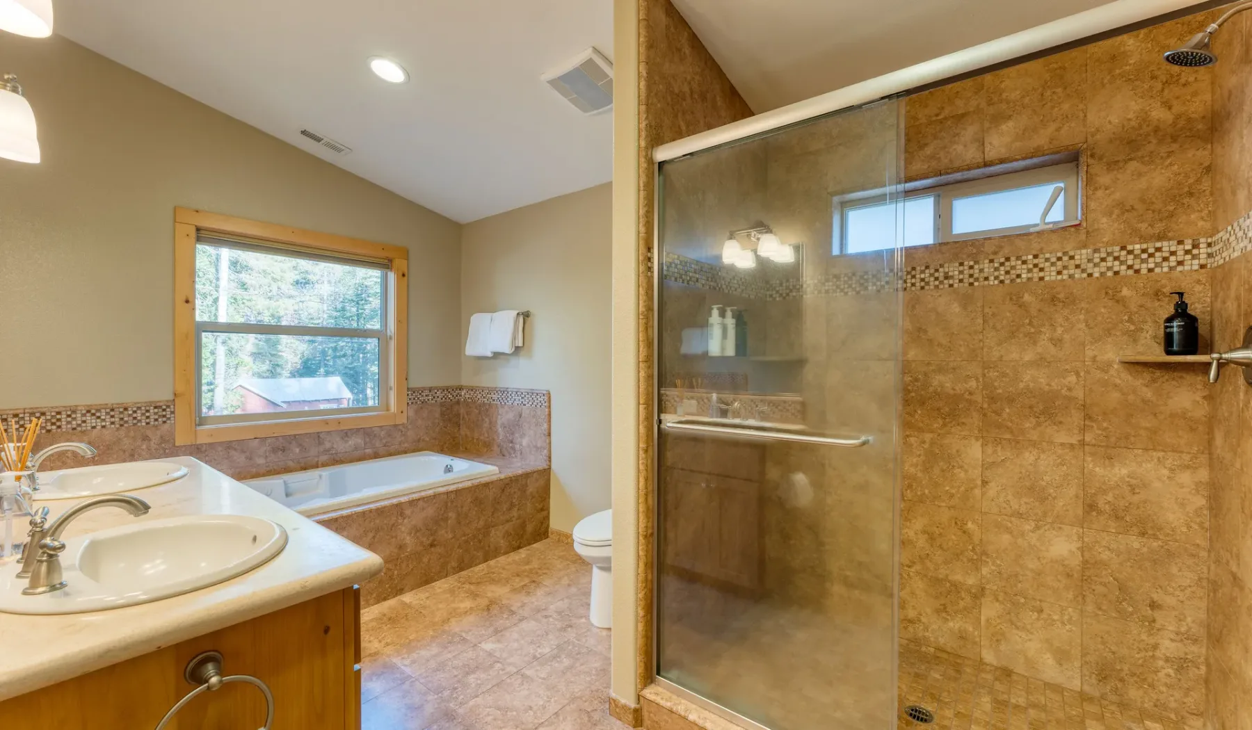 A bathroom with a bathtub beneath a window and a glass-enclosed shower.