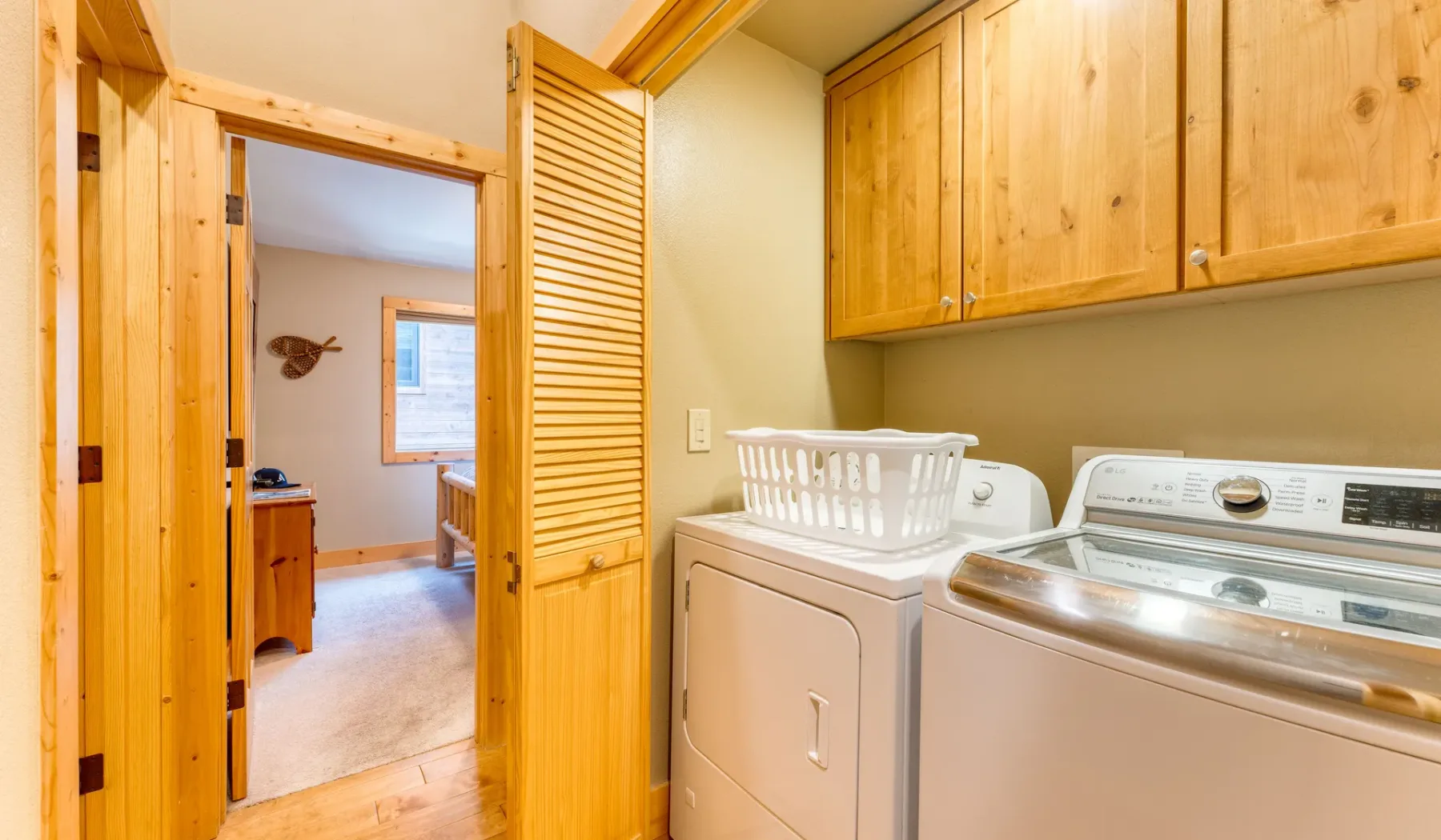 A laundry room with a washer and dryer beneath wooden cabinets.