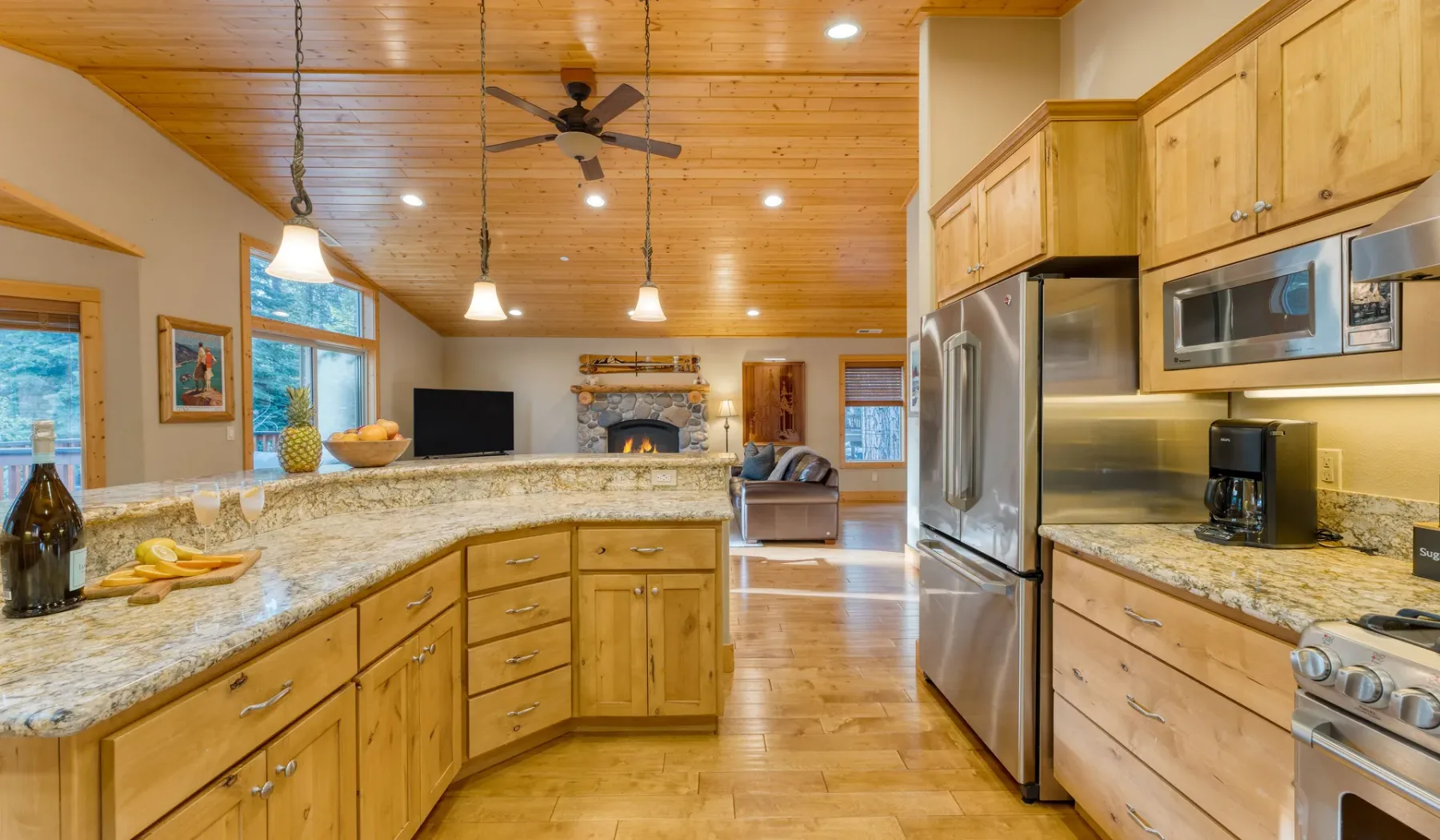 A spacious kitchen with wooden cabinets, a stone island, and stainless steel appliances.