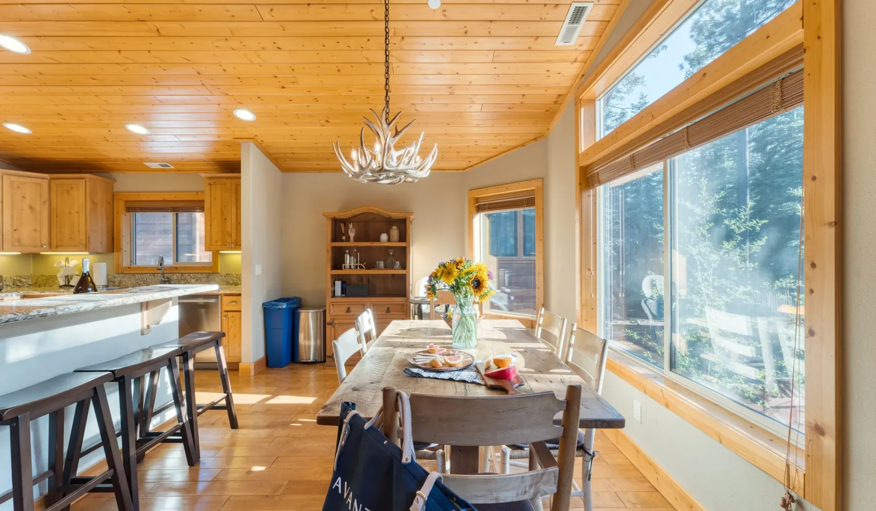 A bright dining area with a wooden table beside large windows.