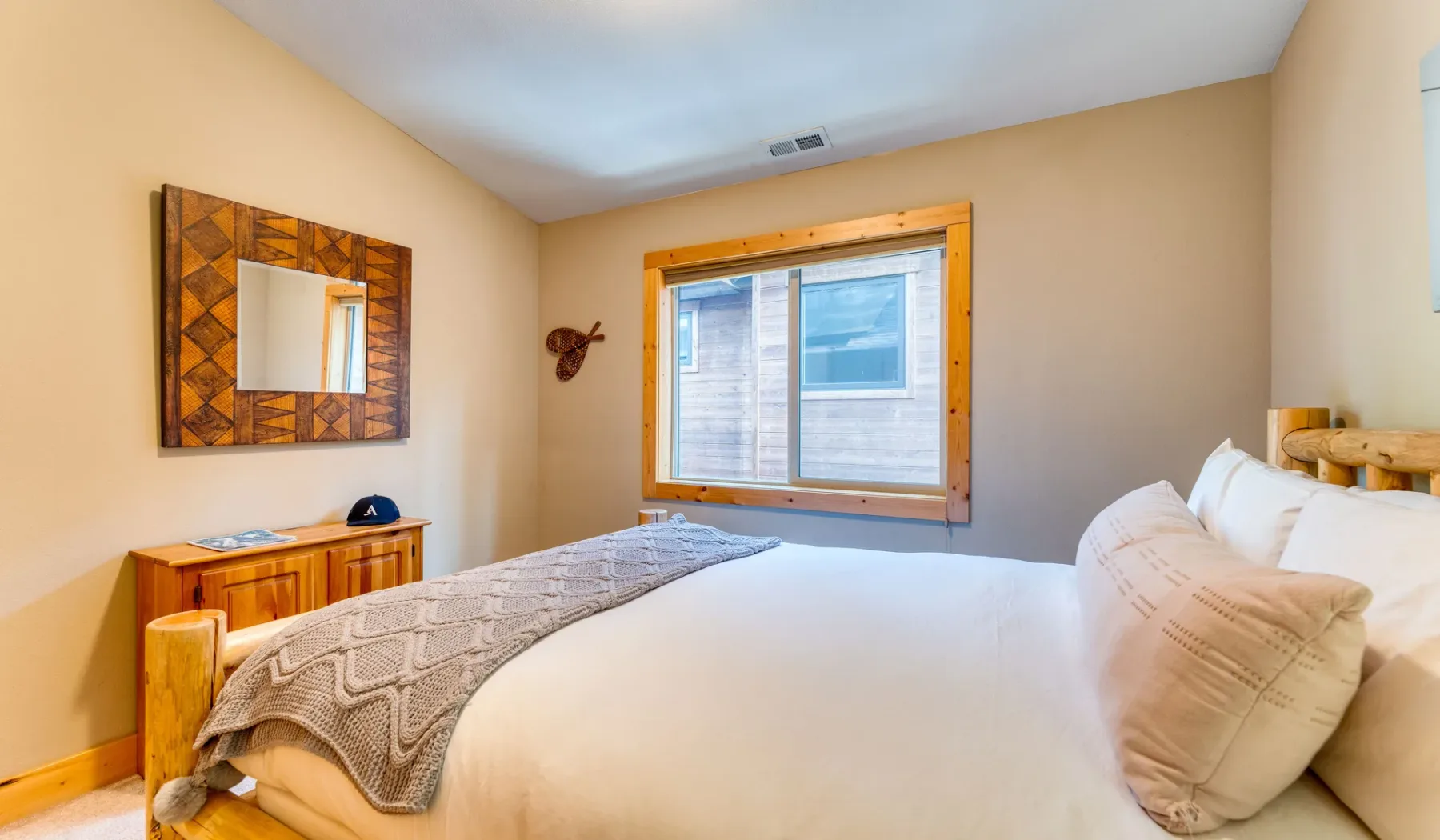 A bedroom with a large bed and a window framed in wood.