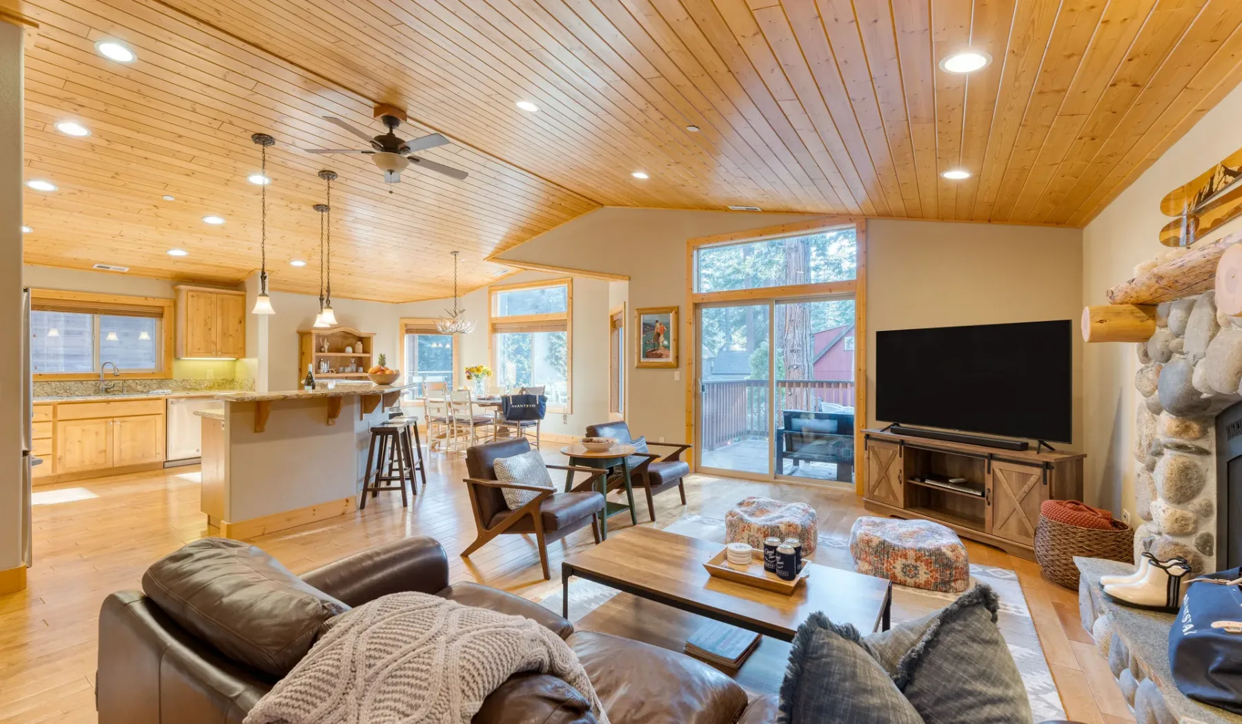 An open-plan living room and kitchen with seating, a dining table, and a television.