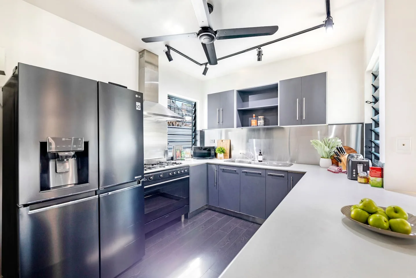 Una cocina moderna con armarios oscuros y una amplia encimera blanca.