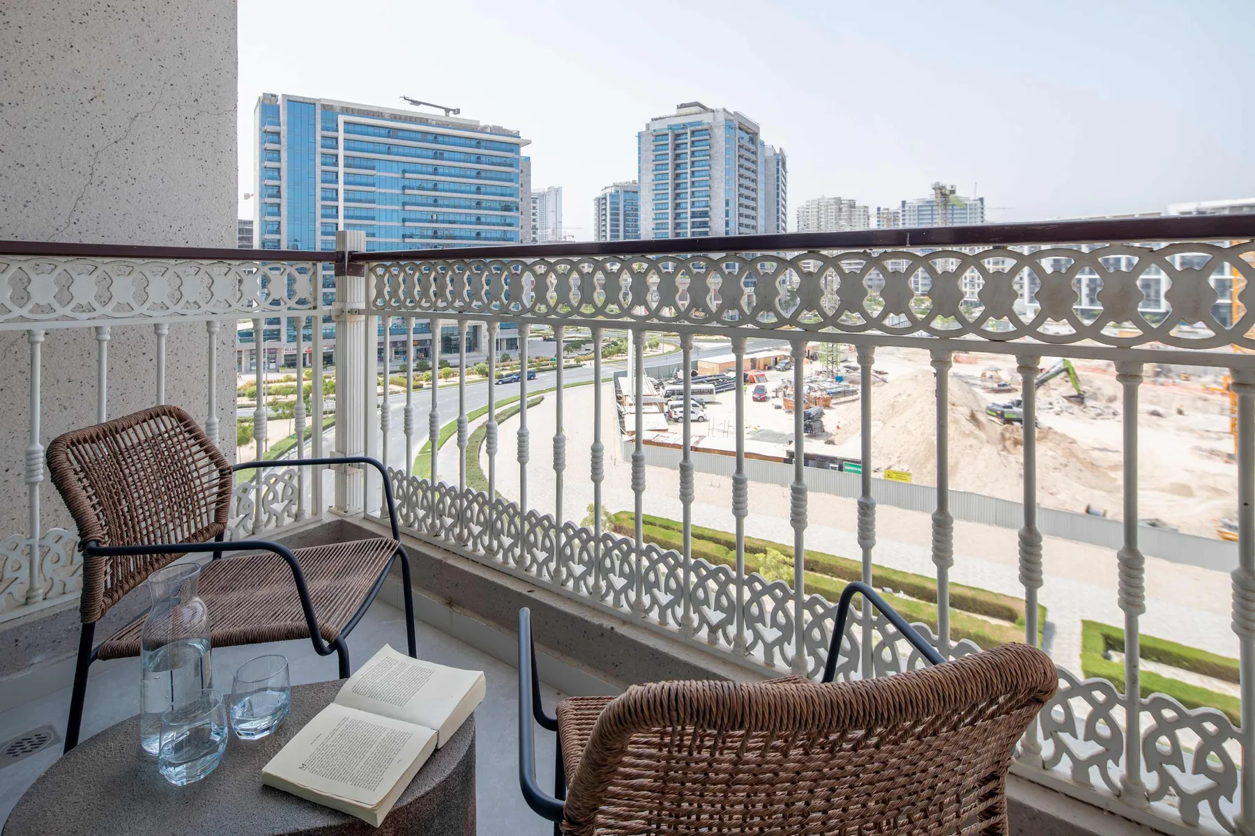 A balcony seating area overlooks modern buildings and a construction site.