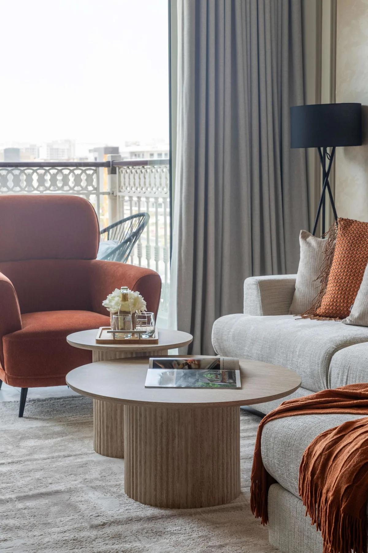 A living room with seating, two round coffee tables, and floor-to-ceiling curtains.