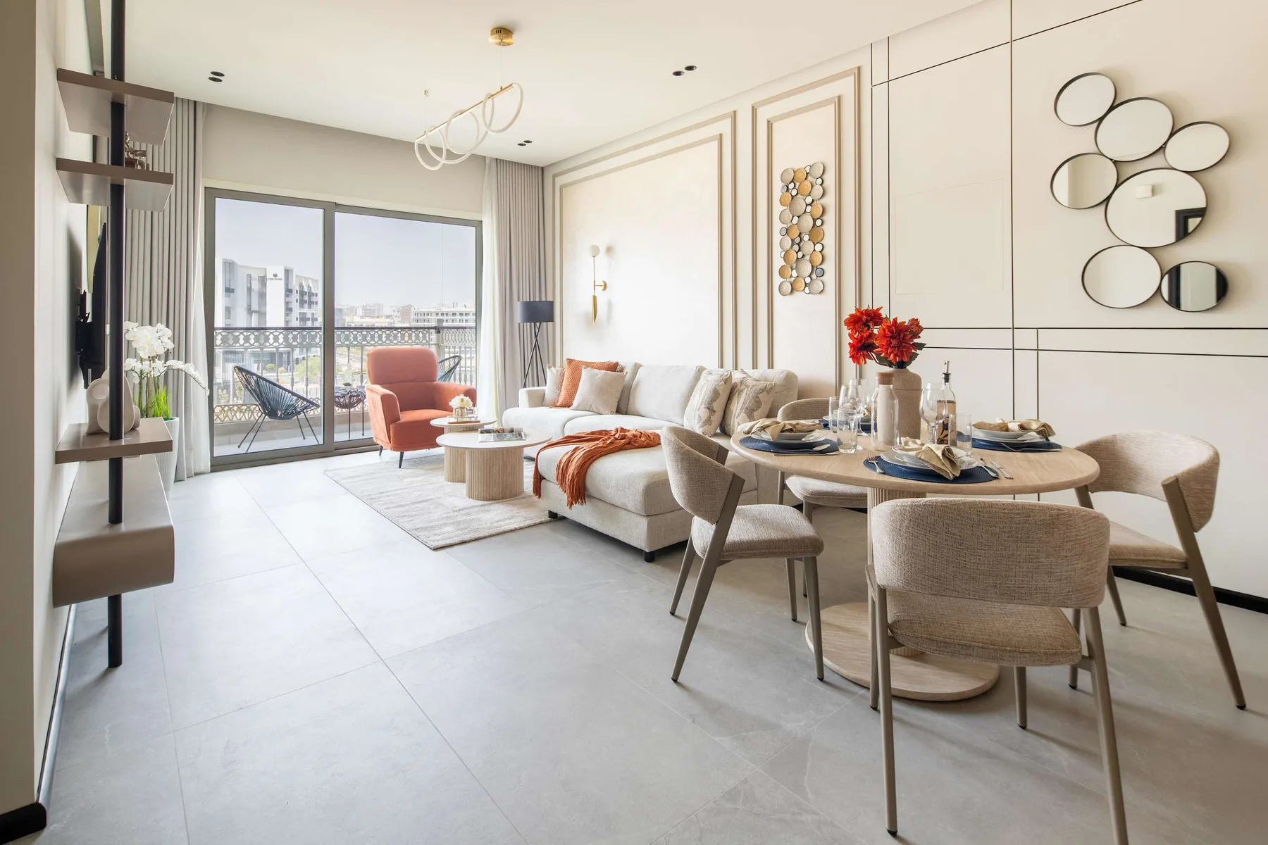 A bright living and dining area with a sofa, dining table, and balcony doors.