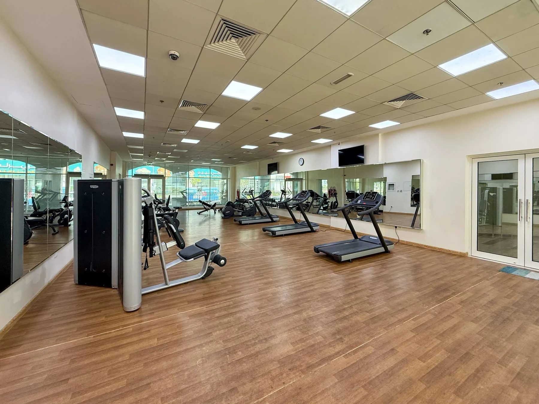 A gym with exercise machines and treadmills sits beside mirrored walls.