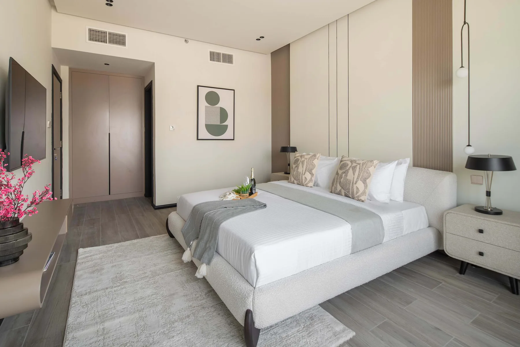 A bedroom with a large bed, bedside lamps, and a light area rug.