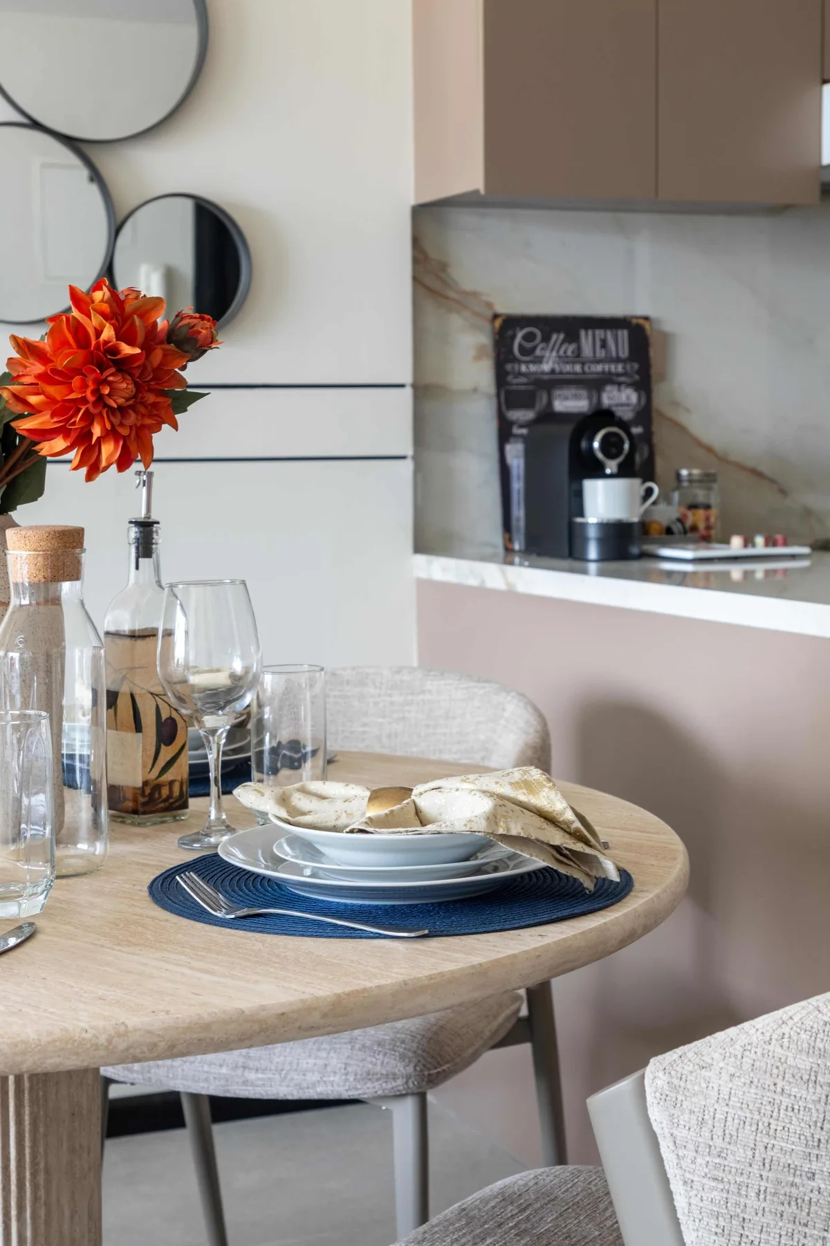 A dining area with a round table set beside a kitchen coffee station.