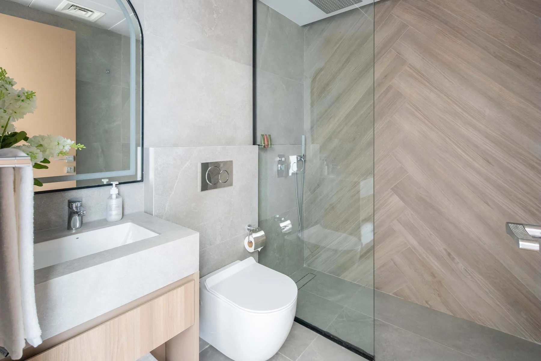 A modern bathroom with a vanity, toilet, and glass shower.