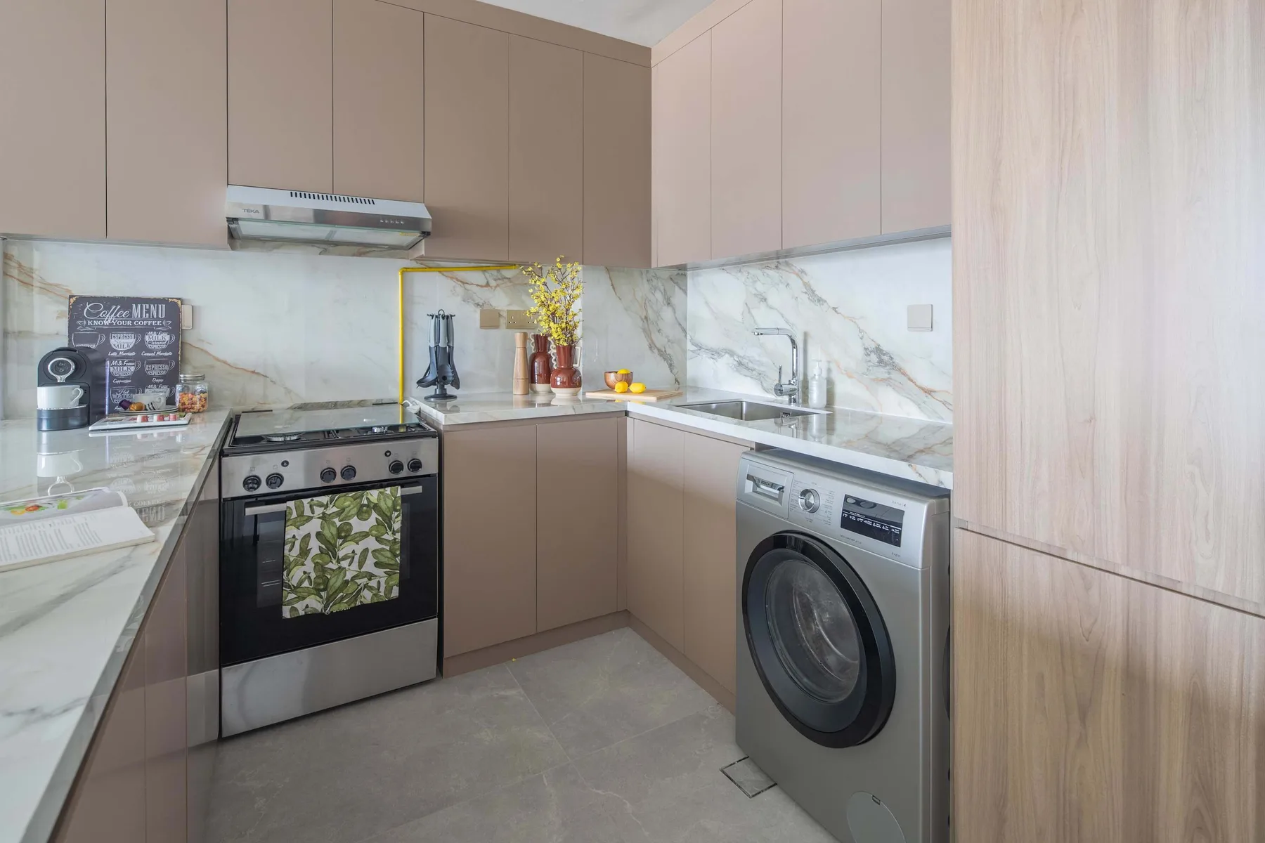 A modern kitchen with taupe cabinets, a stove, and a washing machine.