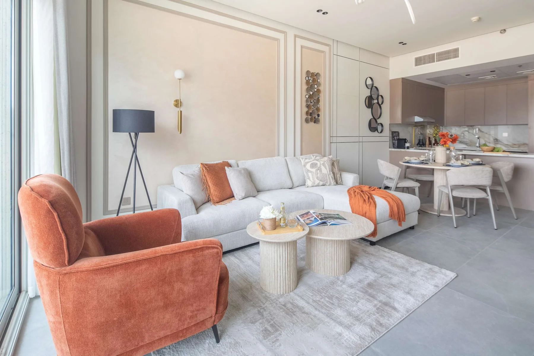 A bright living room with seating and a dining area beside the kitchen.