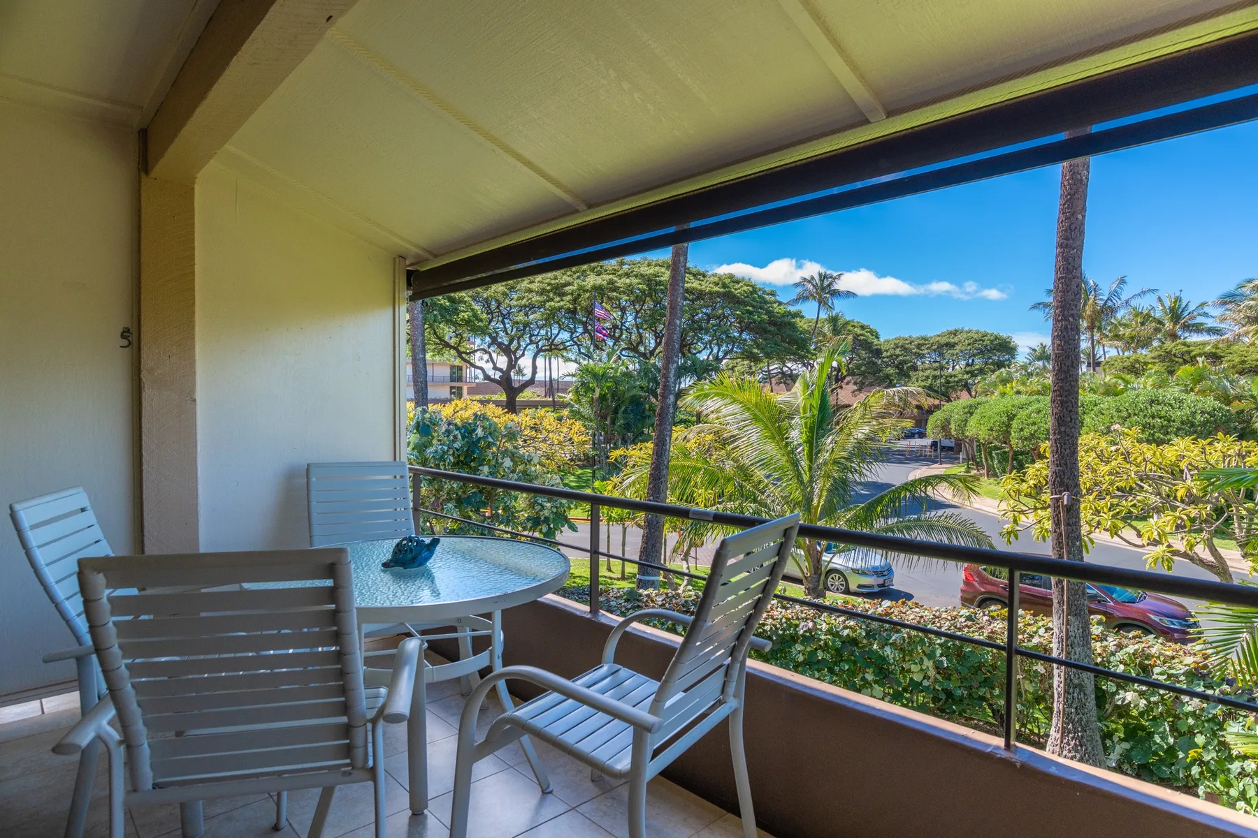 Un balcón cubierto tiene asientos al aire libre y vistas de vegetación tropical.