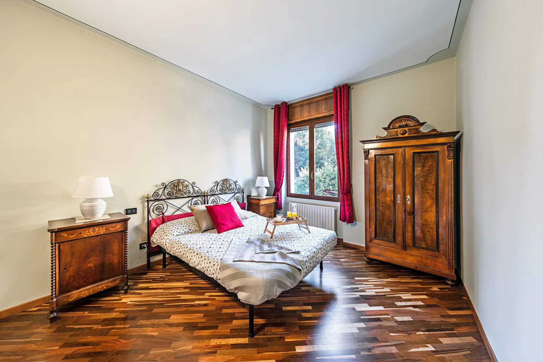 Un dormitorio con una cama, mesitas de noche y un armario alto de madera.
