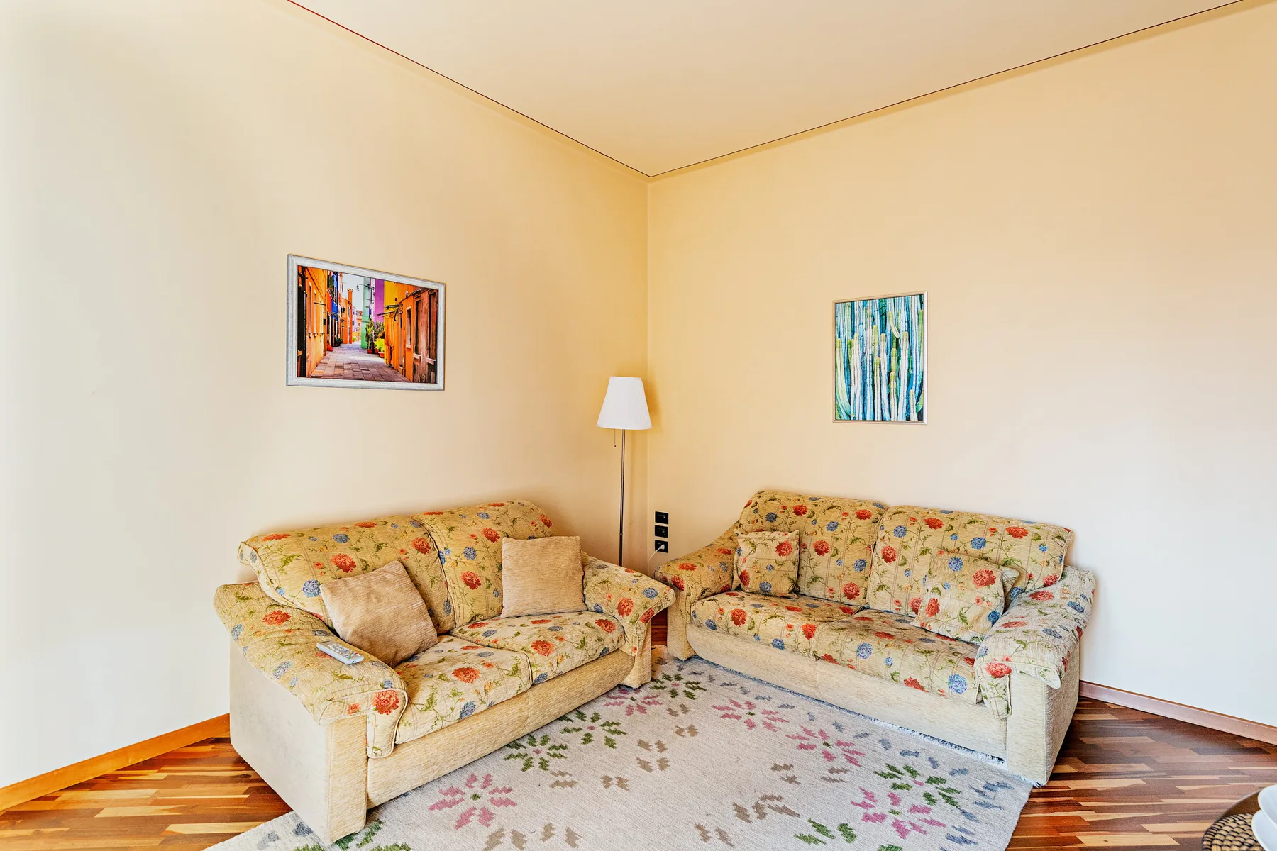Una sala de estar con asientos estampados de flores y cuadros en la pared.
