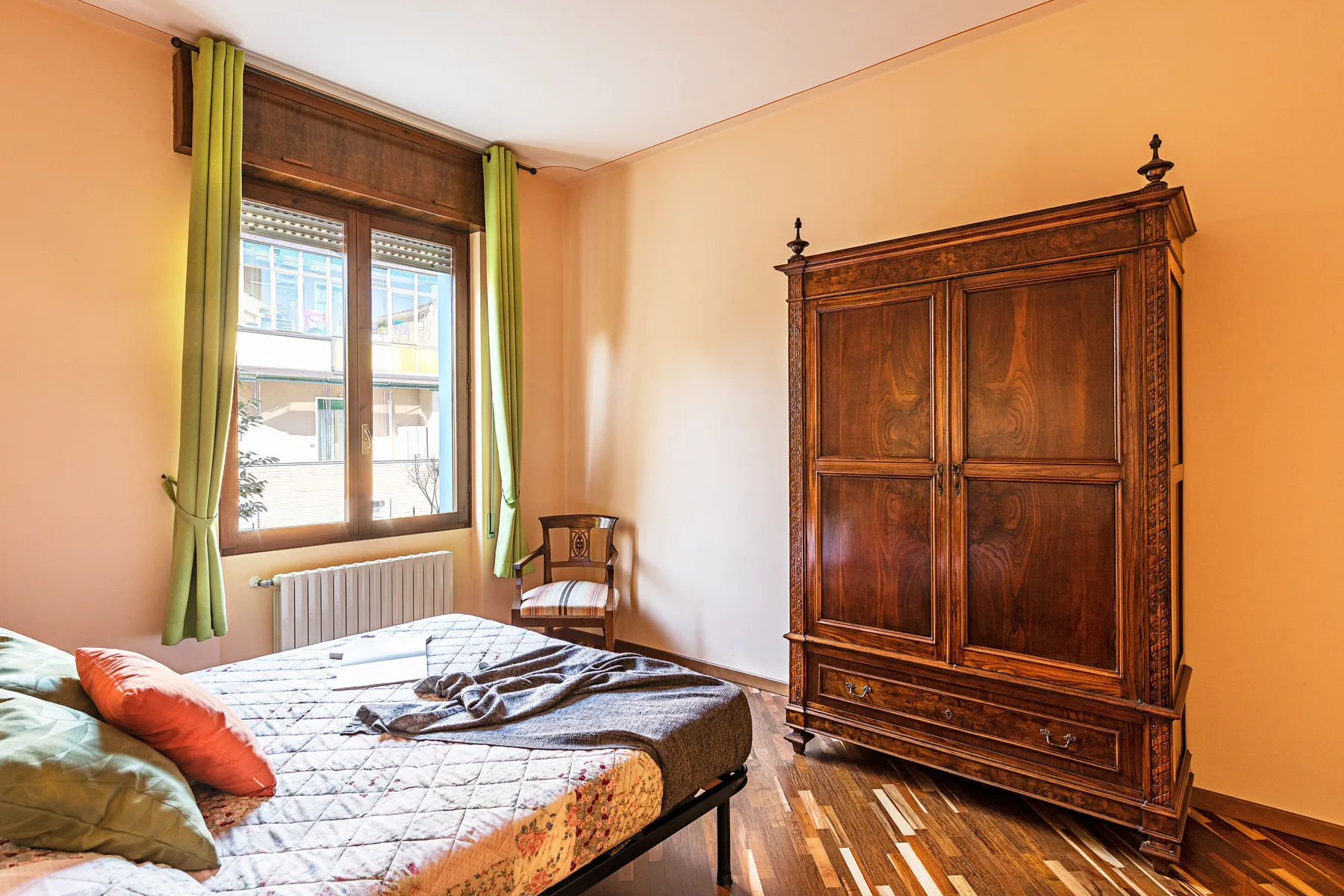 Un dormitorio con una cama junto a una ventana y un gran armario de madera.