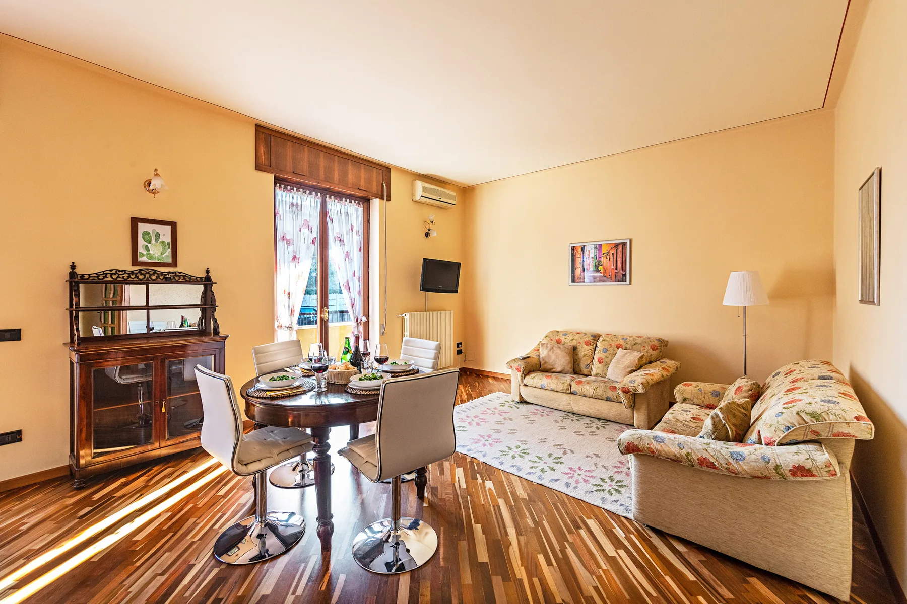 Una sala de estar con mesa de comedor, asientos tapizados y una alfombra estampada.