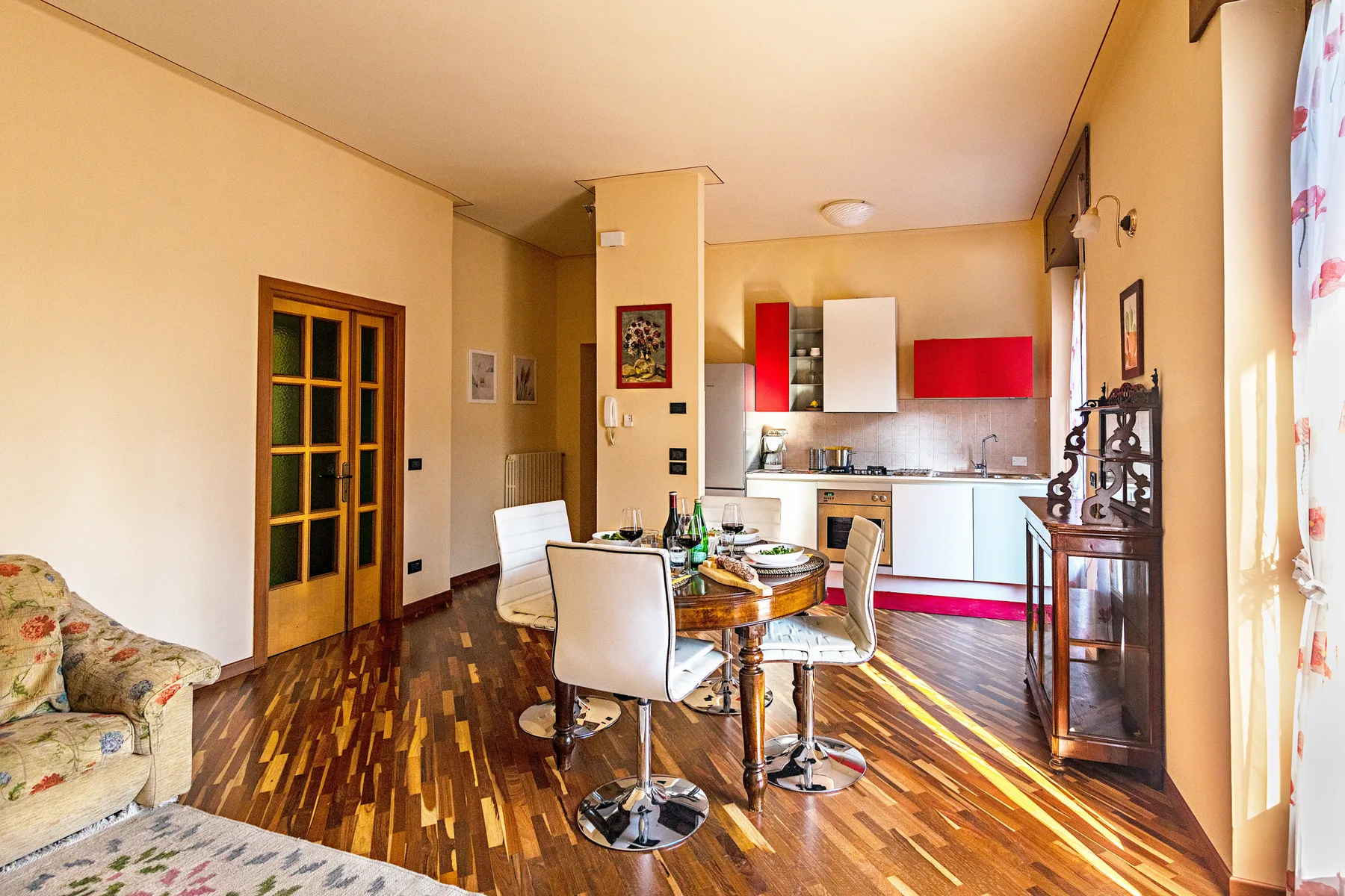 Un comedor se abre a una cocina, con una mesa redonda y sillas.