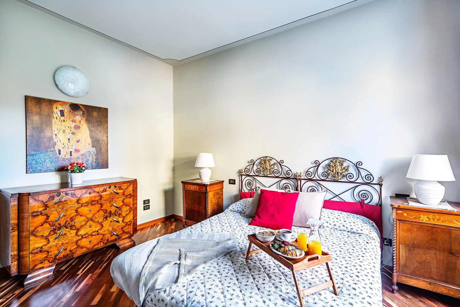 Un dormitorio con una colcha estampada, un cabecero ornamentado y muebles de madera.