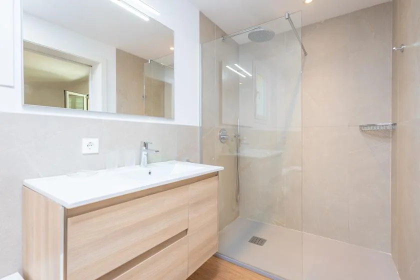 Un baño luminoso con un amplio tocador y una ducha de vidrio.