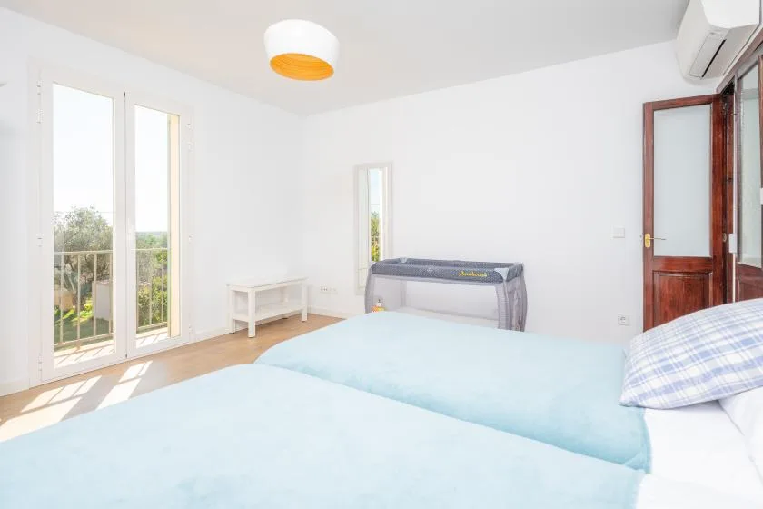 Un dormitorio luminoso con dos camas y puertas de vidrio que dan a un balcón.