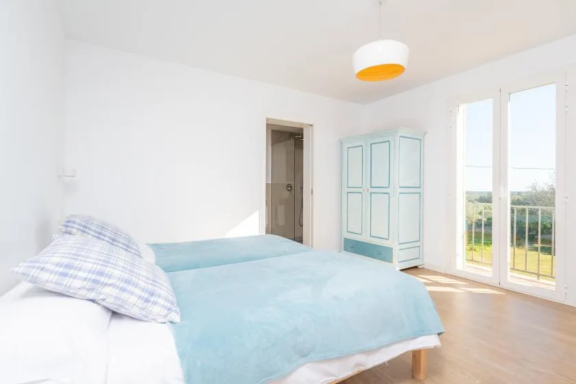 Un dormitorio luminoso con una cama y puertas de vidrio altas que dan a un balcón.