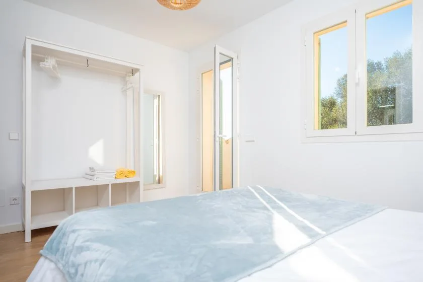 Un dormitorio luminoso con una cama y una ventana.